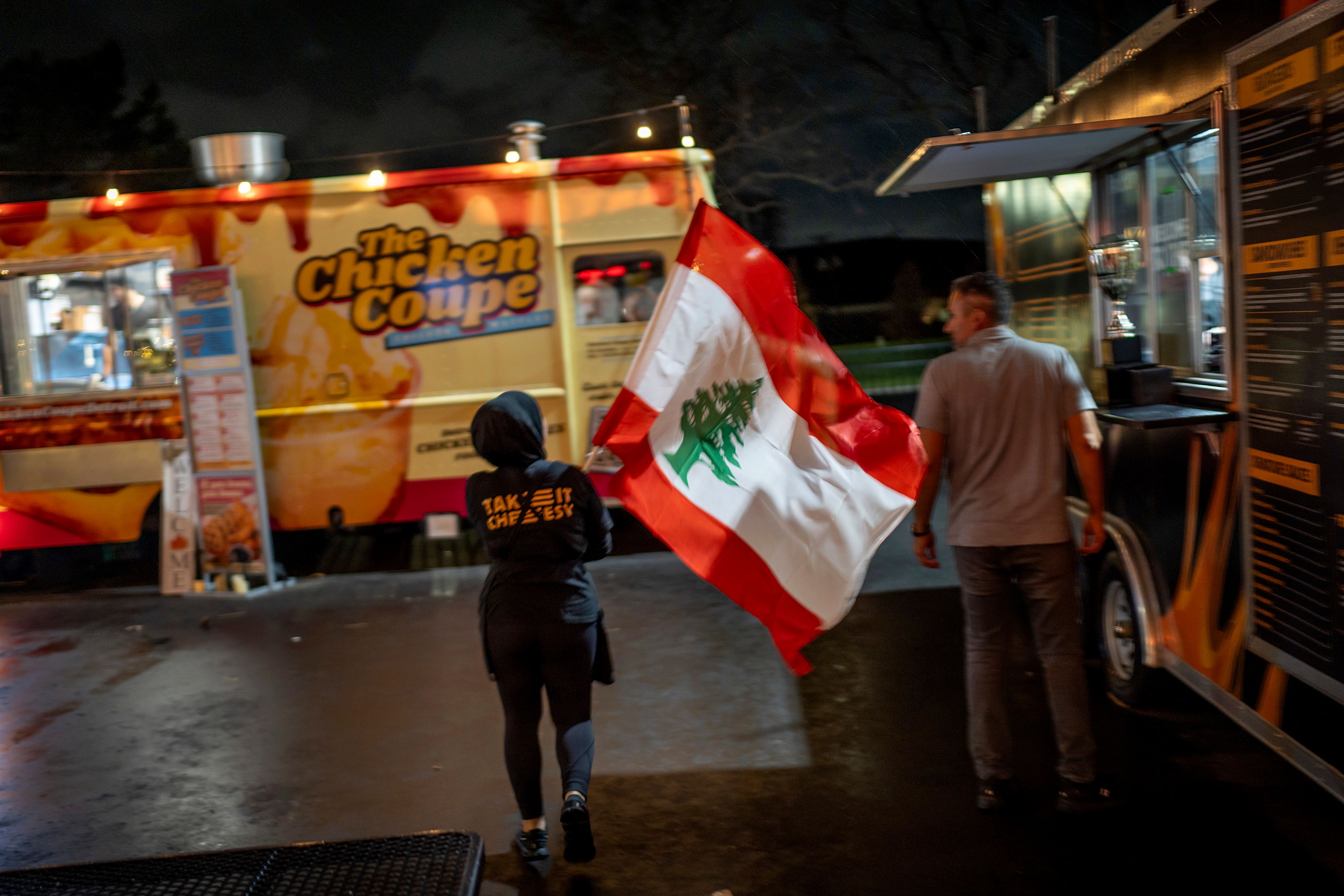 Ameera Amad waves the Lebanese flag outside an American Muslims and Allies election night watch party Tuesday, Nov. 5, 2024, in Dearborn, Mich., the nation's largest Arab-majority city. (AP Photo/David Goldman)