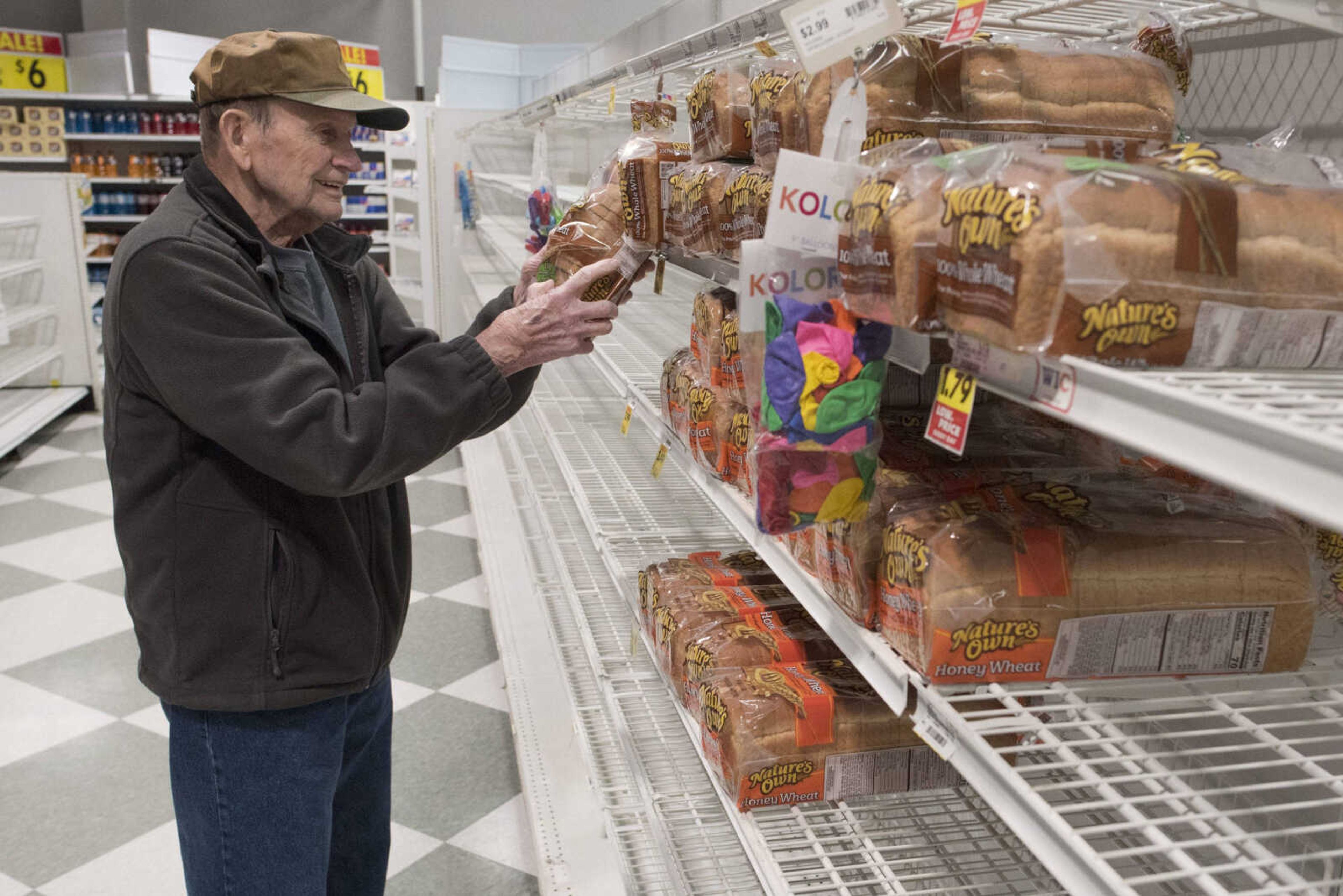 A shopper who asked to remain unnamed chooses a loaf of whole wheat bread from a shelf at Schnucks during the store's first hour of business Wednesday in Cape Girardeau. In an effort to provide senior shoppers with easier access to groceries amid coronavirus-related supply shortages, Schnucks made its first hour of business limited to customers of ages 60 and older beginning Wednesday.