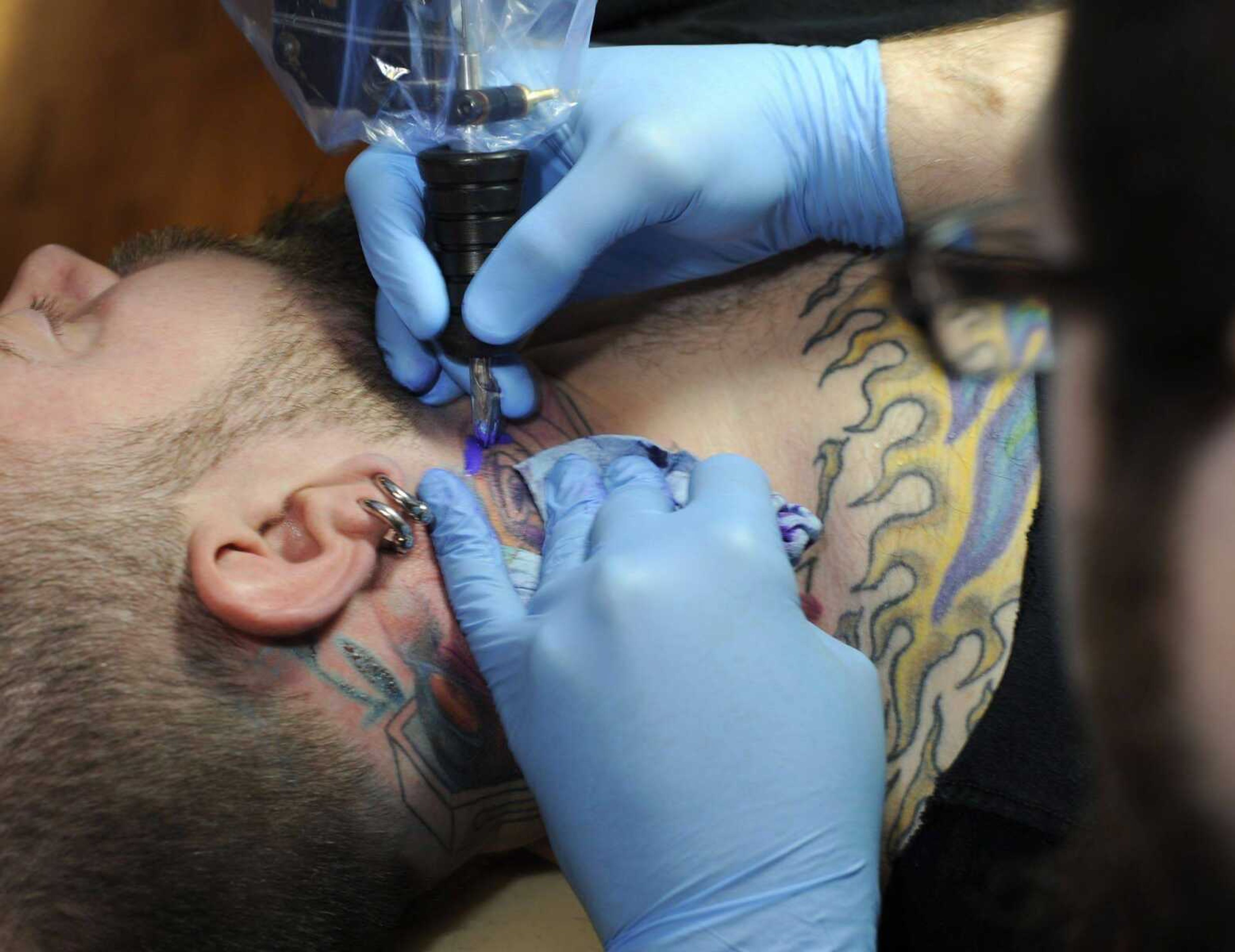 Chris Hester gets a tattoo on his neck from Andy Estes on Thursday at Flesh Hound in Cape Girardeau. (Fred Lynch)