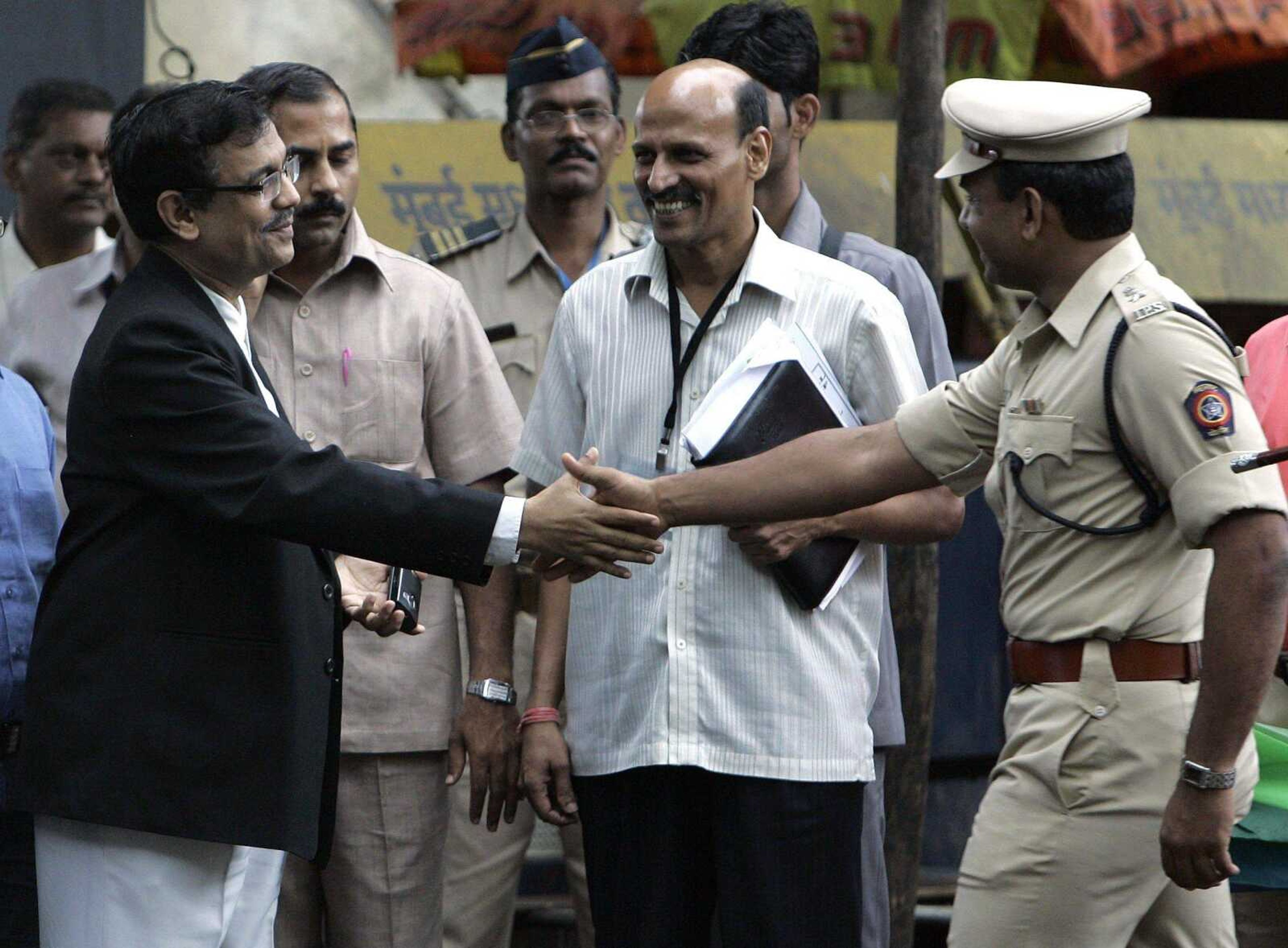 Public prosecutor Ujjwal Nikam, left, shakes hands with a police officer Monday as he exits a special court hearing the terror attacks case in Mumbai, India. The surviving gunman from the attacks gave a detailed account of the plot and his role in the rampage. (Rajanish Kakade ~ Associated Press)