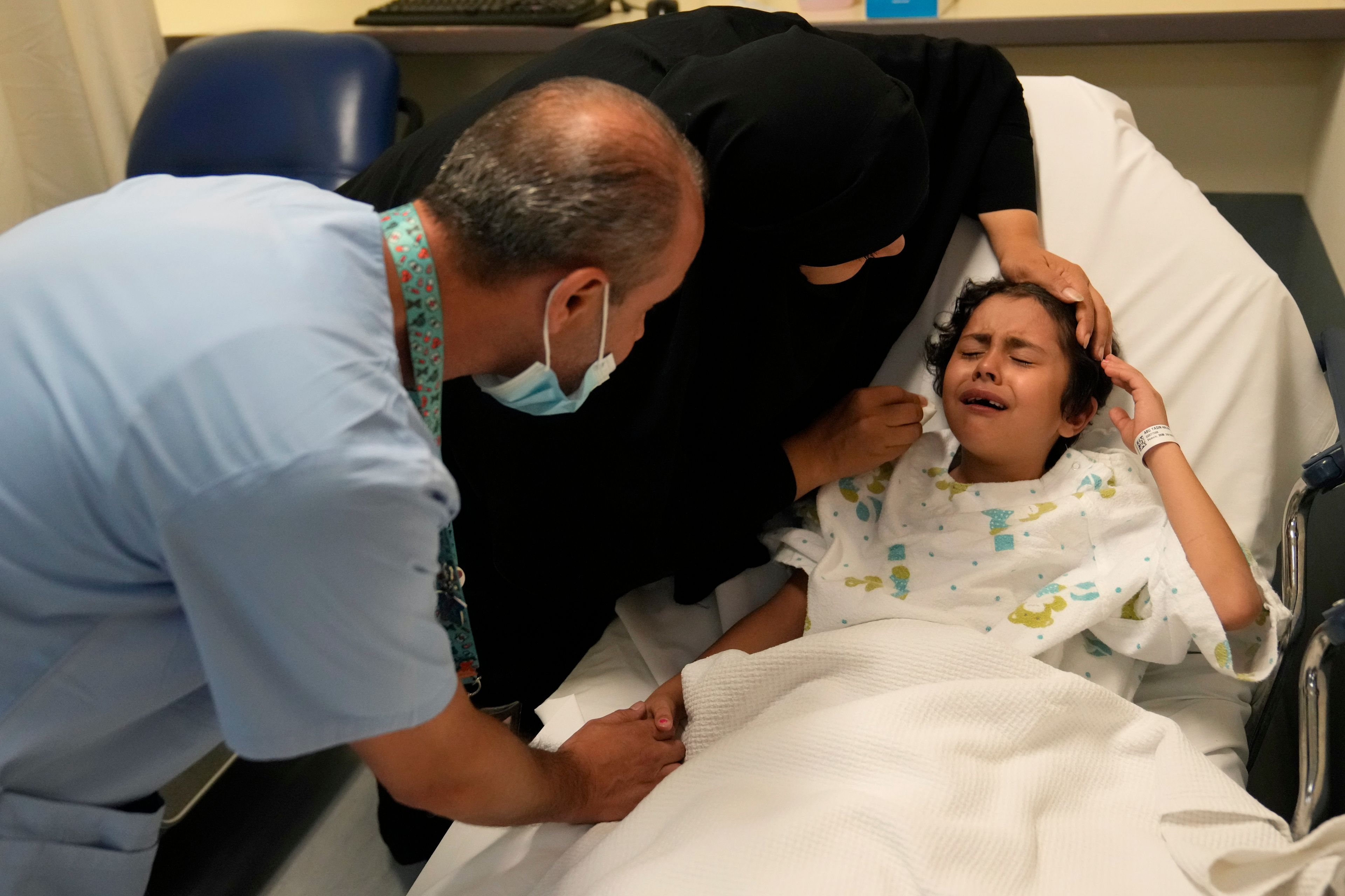 Palestinian girl Halima Abou Yassine, 7, who was brought to Lebanon from Gaza for treatment after an Israeli strike left her near death with a gaping wound in her skull, cries as she lies on a hospital bed ahead of a surgery on her head at the American University of Beirut Medical Center (AUBMC), in Beirut, Lebanon, Monday, July 15, 2024. (AP Photo/Hussein Malla)