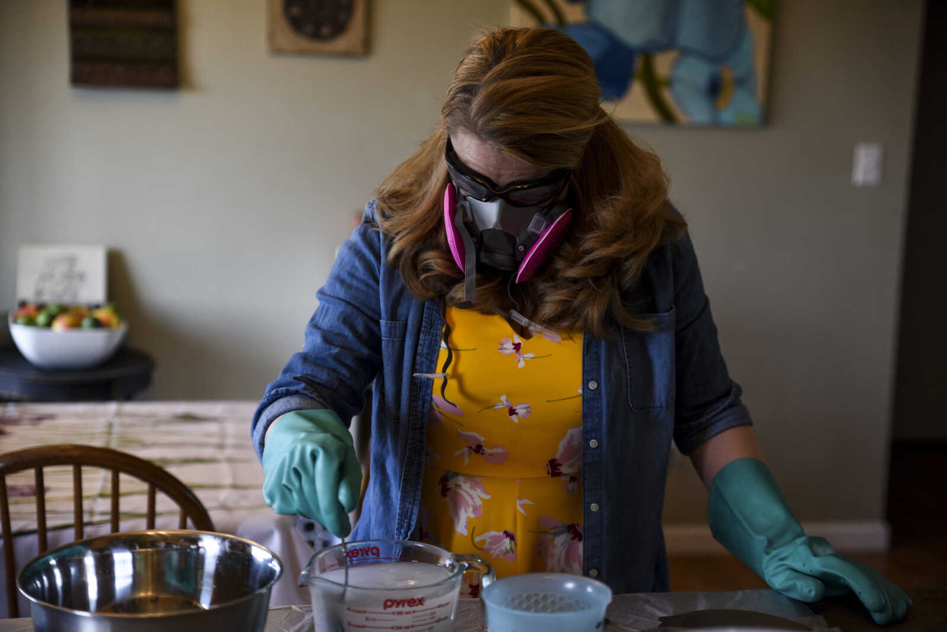 Breanna Stone wears rubber gloves, goggles and a gas mask as she mixes lye in warm water Tuesday, May 1, 2018, in her home in Jackson.