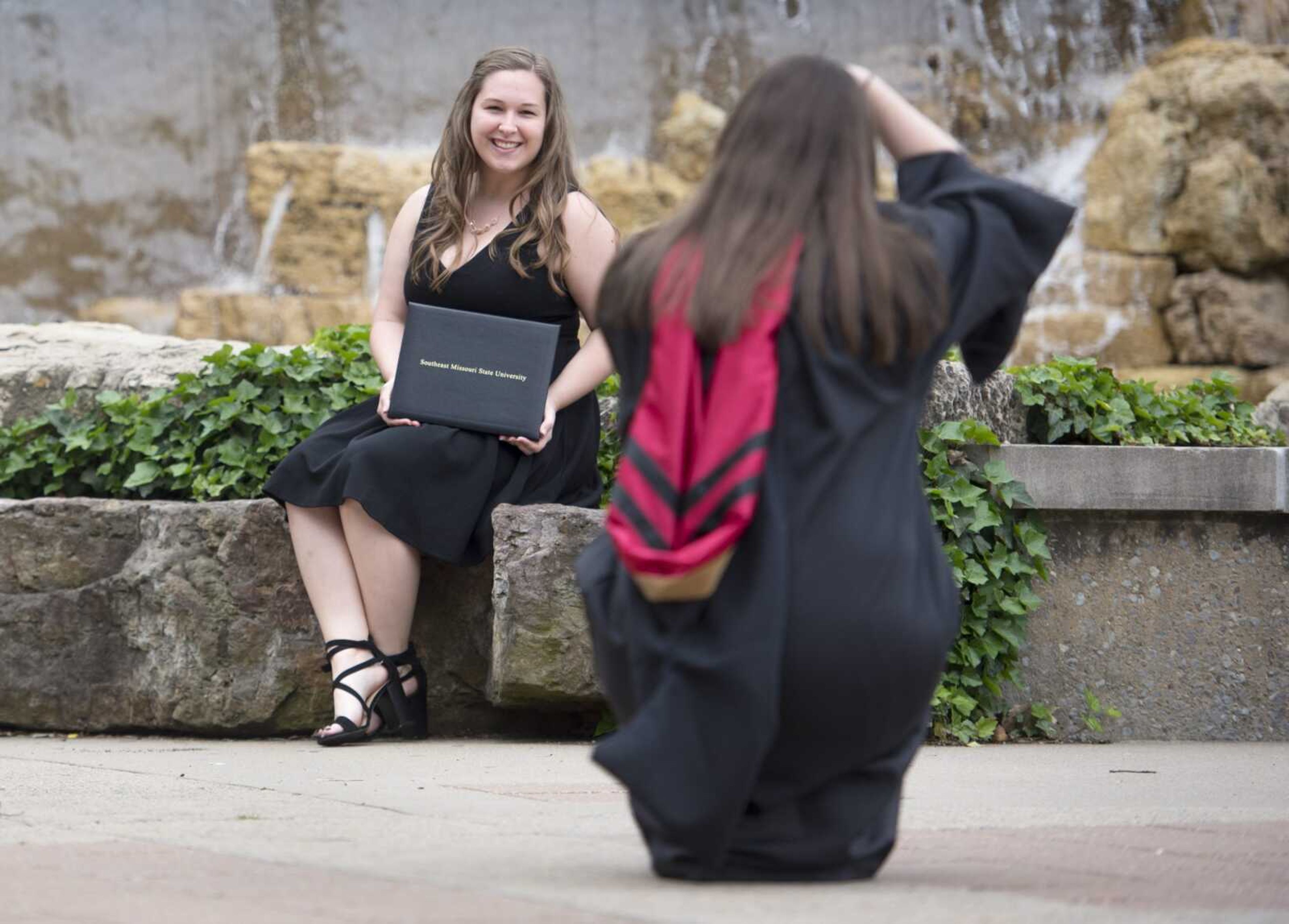 Mallory Westerman of Chester, Illinois, poses for a photo taken by fellow Southeast Missouri State University graduate Adrienne Webery of St. Mary, Missouri, on Monday in front of a fountain near Kent Library on the Southeast campus. At the completion of the spring semester, both graduates earned master's degrees in business administration with a focus in accounting. With them Monday was Lena Kuehmel, not pictured, of Aachen, Germany, who earned a dual master's degree in business administration from Southeast and a Master of Arts from Aachen University of Applied Science. The graduates posed in front of a fountain that had been switched off since March 24 for necessary repairs, according to the university. After students took to Facebook to request the fountains be turned on again for the purpose of taking graduation photos, university officials turned the fountain near the library back on and said it will remain on through May 26.