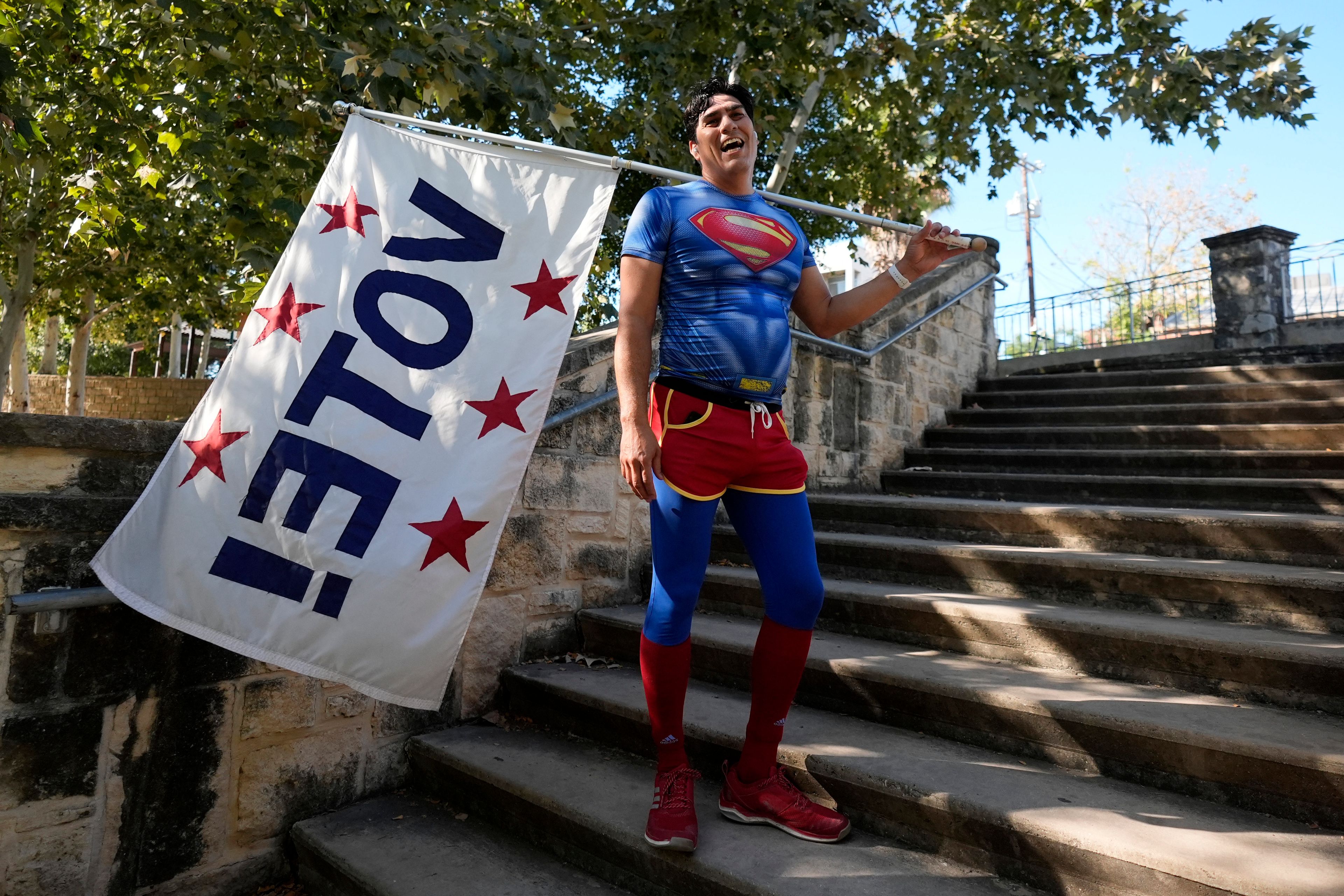 Artist David Alcantar pauses during a run with his "VOTE" flag on the first day of early voting as part of his "Superman Project" that in part encourages people to exercise their right to vote in San Antonio, Monday, Oct. 21, 2024. (AP Photo/Eric Gay)