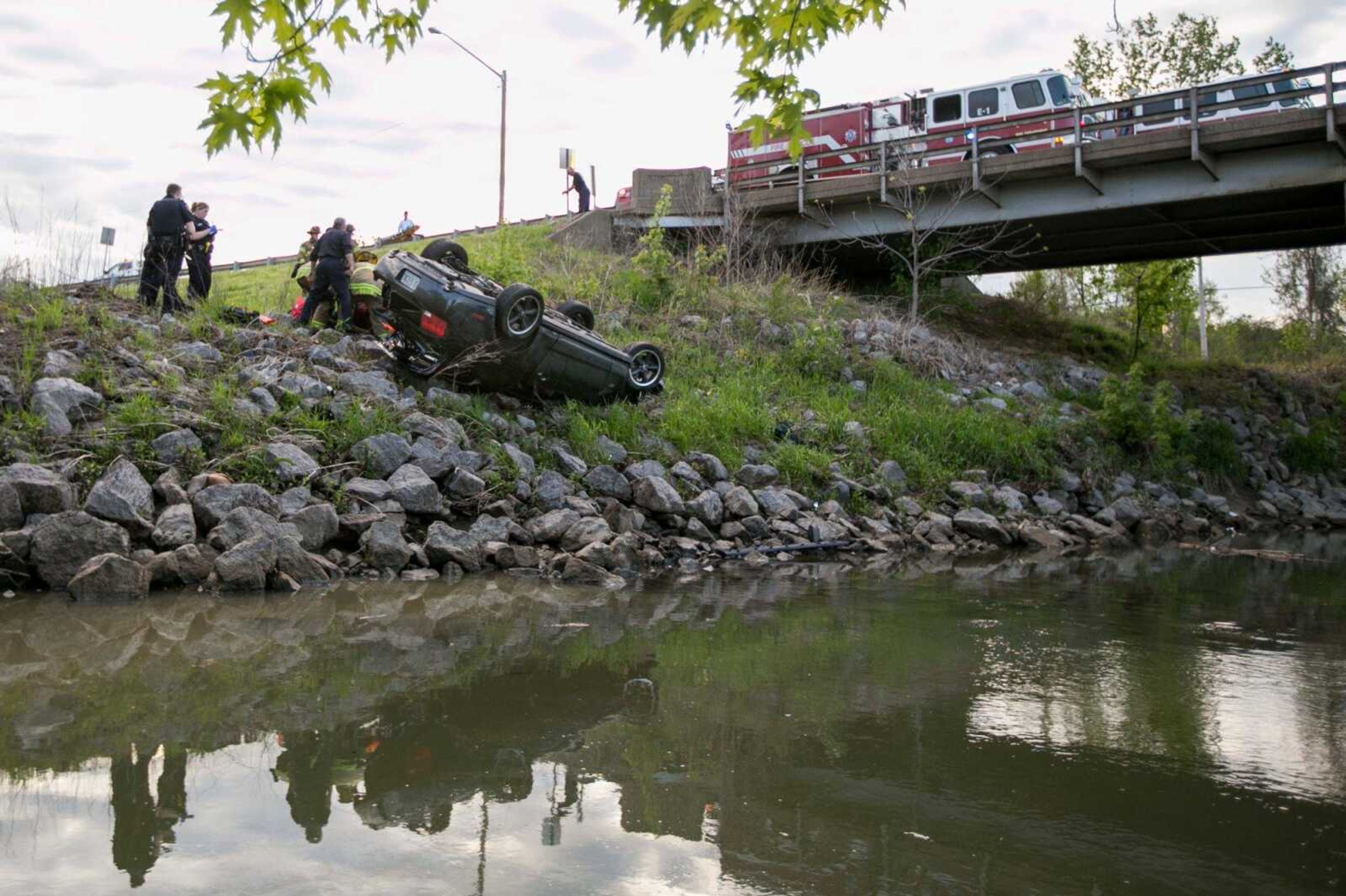 Members of the Cape Girardeau Fire Department and Police Department work to pull a driver from a Ford Mustang after the car went off the Southern Expressway and overturned onto the west bank of Cape LaCroix Creek. Firefighters extricated the driver, who was taken to a hospital. His condition was not released. (Glenn Landberg)