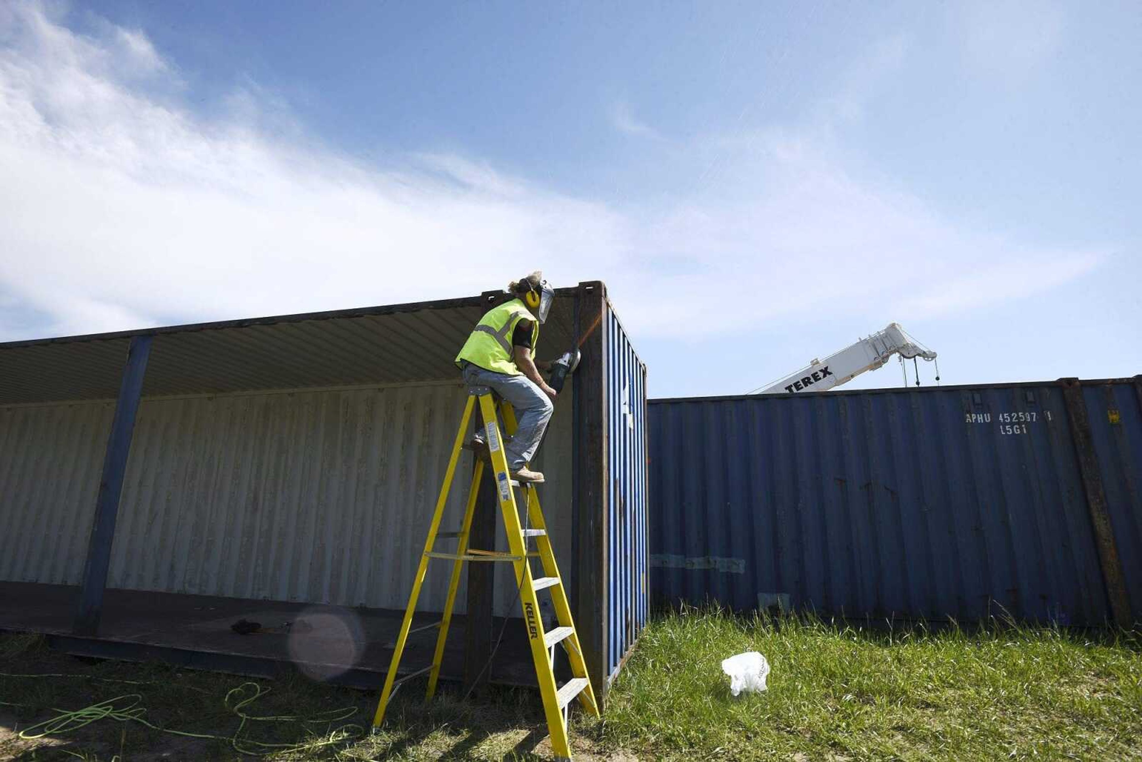 Dennis Lacey of Capital Real Estate Group LLC grinds edges on a shipping container April 25 in Cape Girardeau. A developer was planning to use the containers for a residential project.