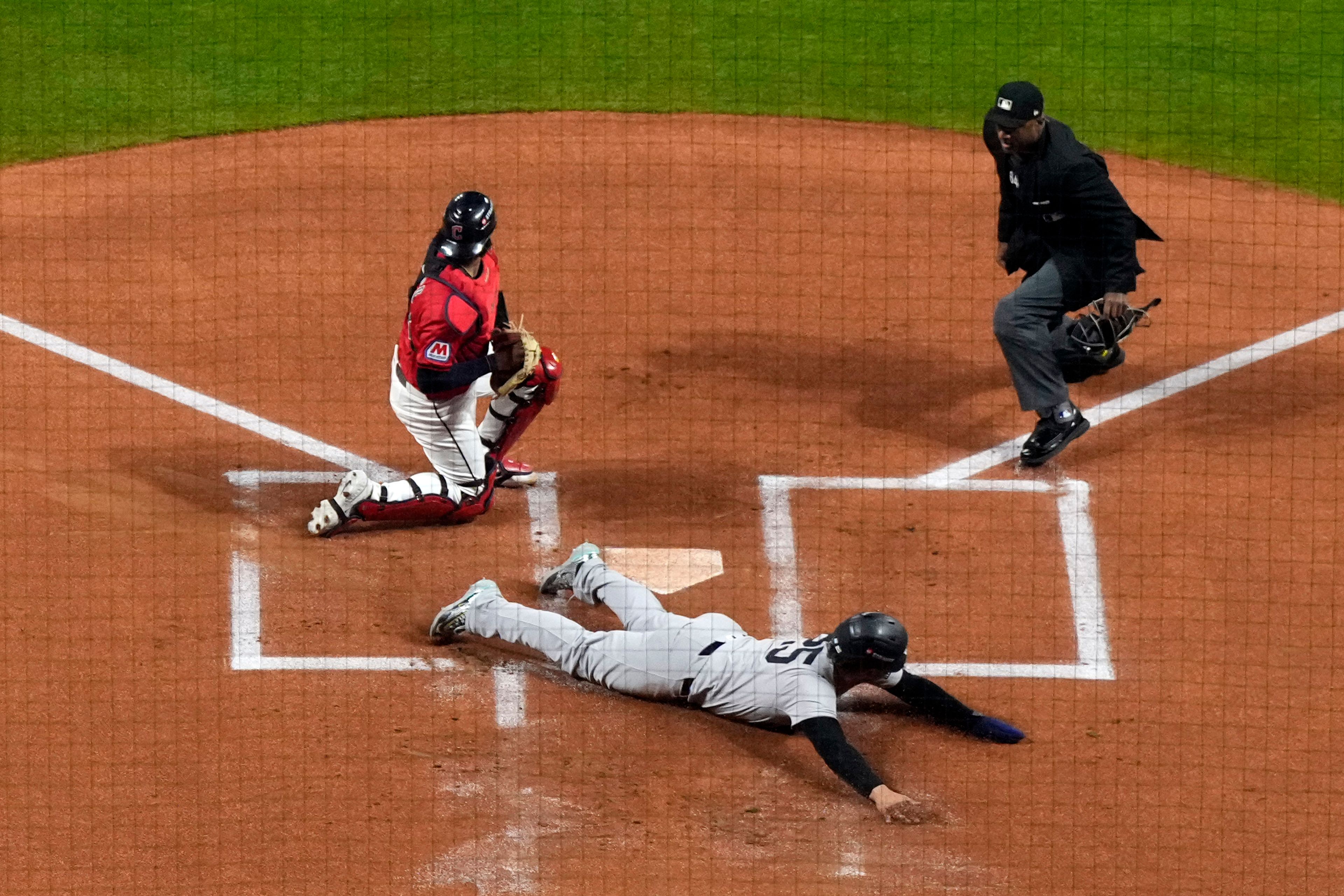 New York Yankees' Gleyber Torres (25) slides across home plate after being tagge out by Cleveland Guardians catcher Bo Naylor during the first inning in Game 5 of the baseball AL Championship Series Saturday, Oct. 19, 2024, in Cleveland. (AP Photo/Godofredo A. Vásquez )