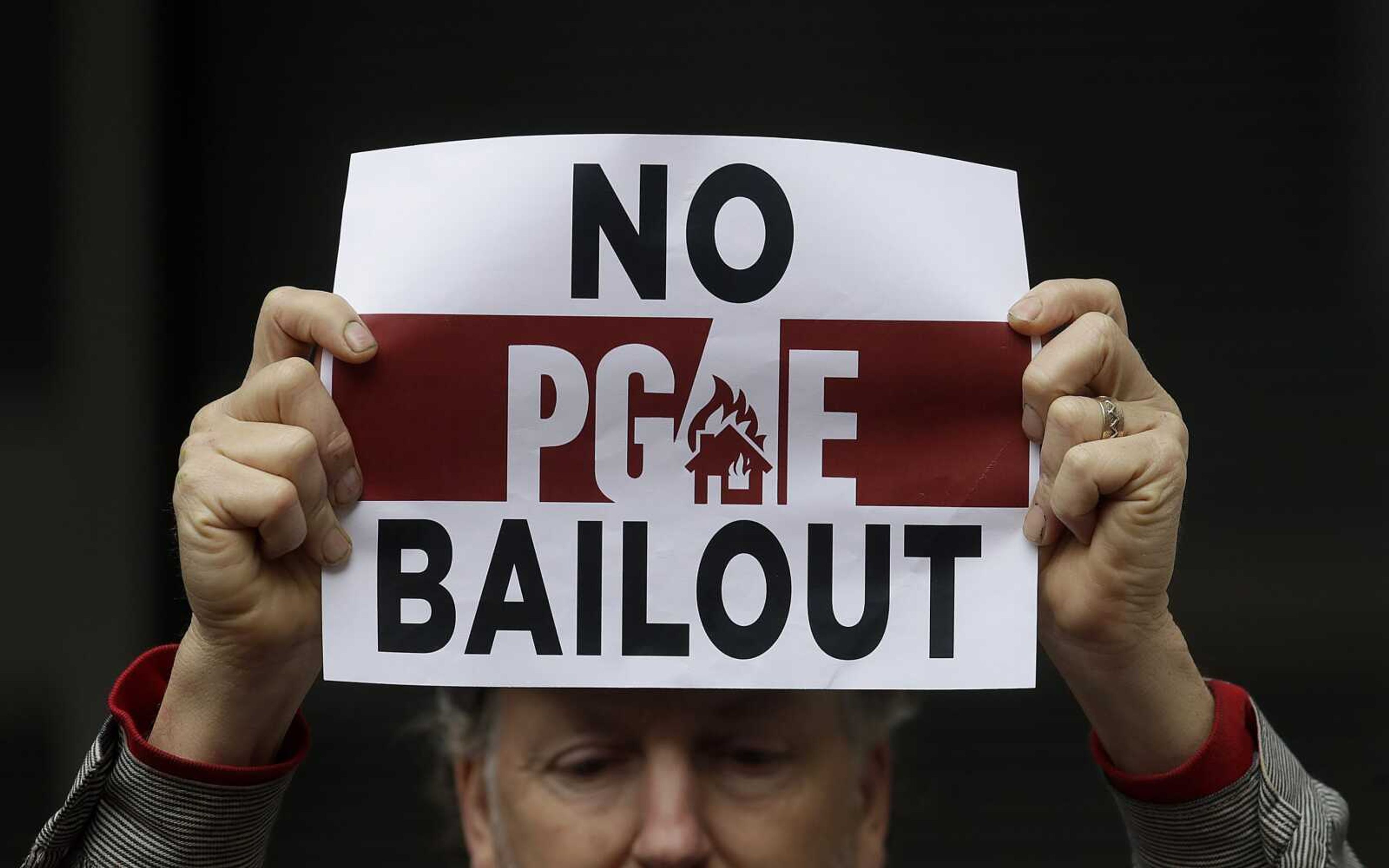 A man holds up a sign at a rally Monday before a California Public Utilities Commission meeting in San Francisco. California regulators have approved a measure allowing Pacific Gas & Electric Corp. to immediately obtain credit and loans while the company is under Chapter 11 bankruptcy protection.