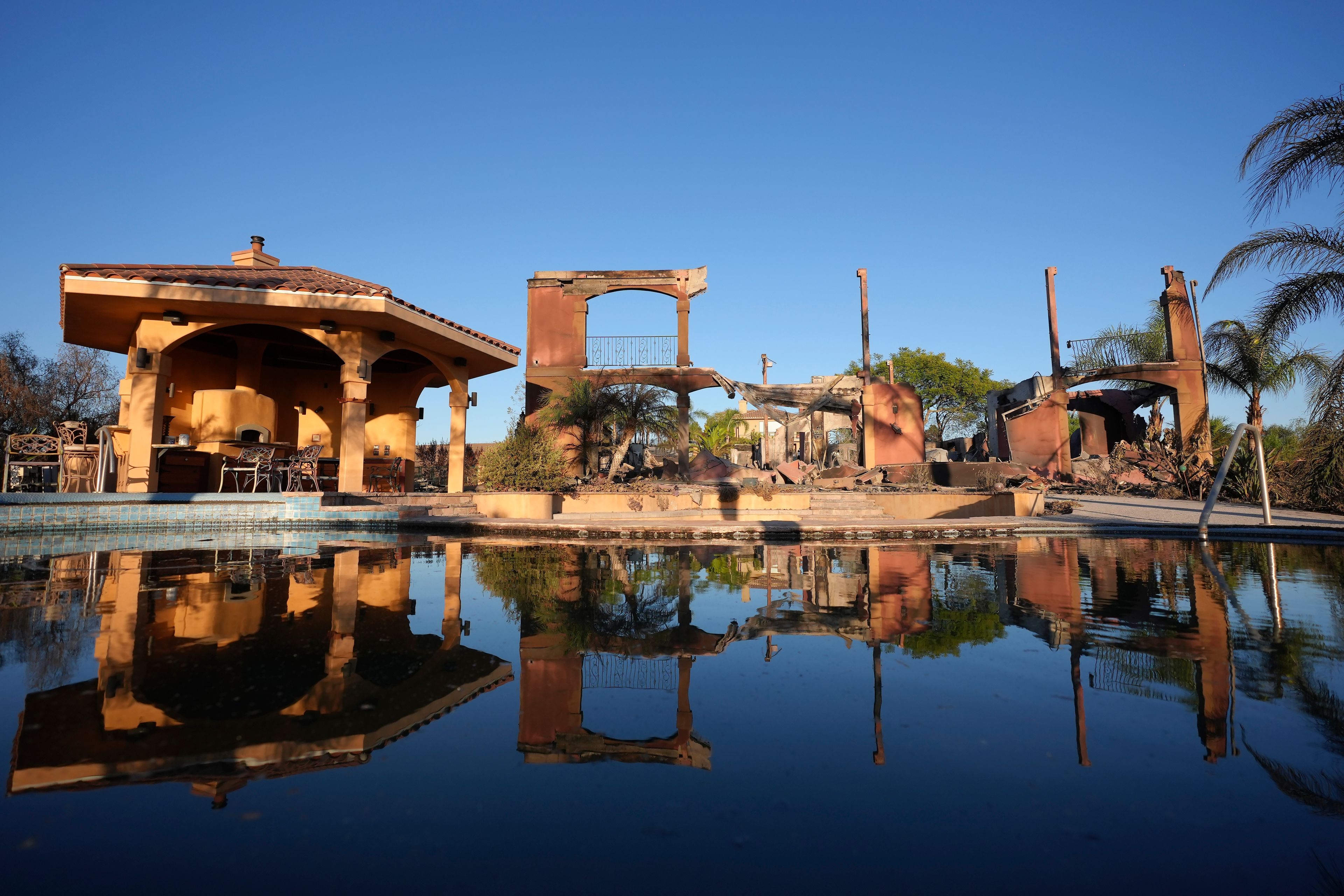 A home destroyed by the Mountain Fire is reflected in a swimming pool in Camarillo, Calif., Nov. 8, 2024. (AP Photo/Jae C. Hong)