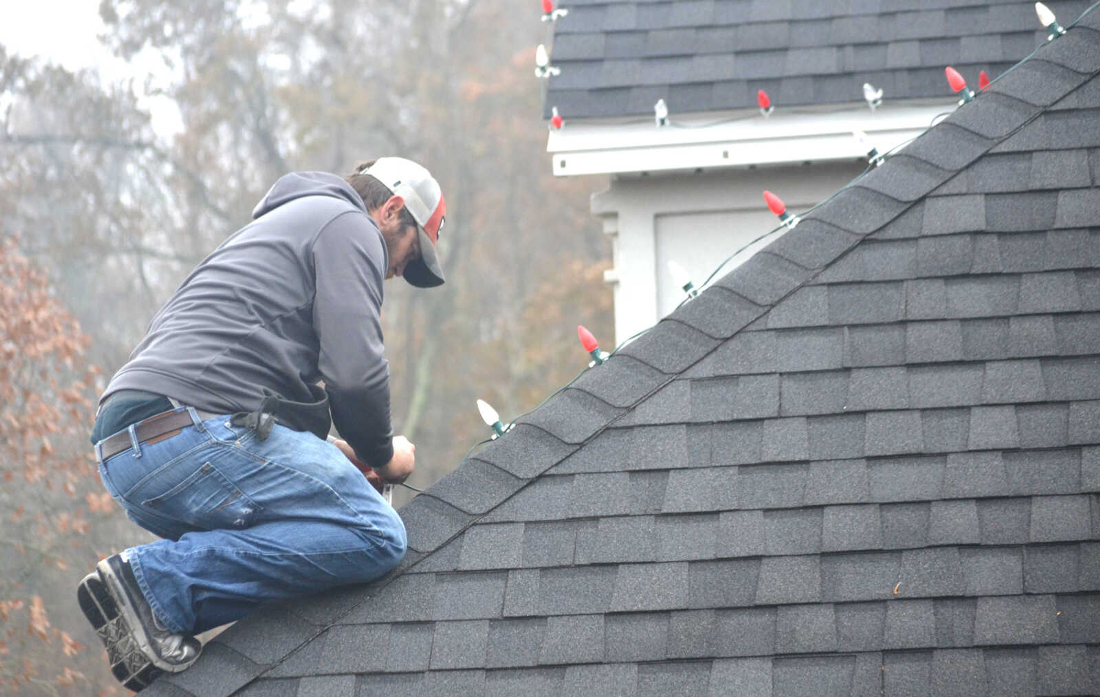 Chris Vernon attaches individual Christmas to shingles on the roof at the home of Vince and Jan Kelley in Cape Girardeau.