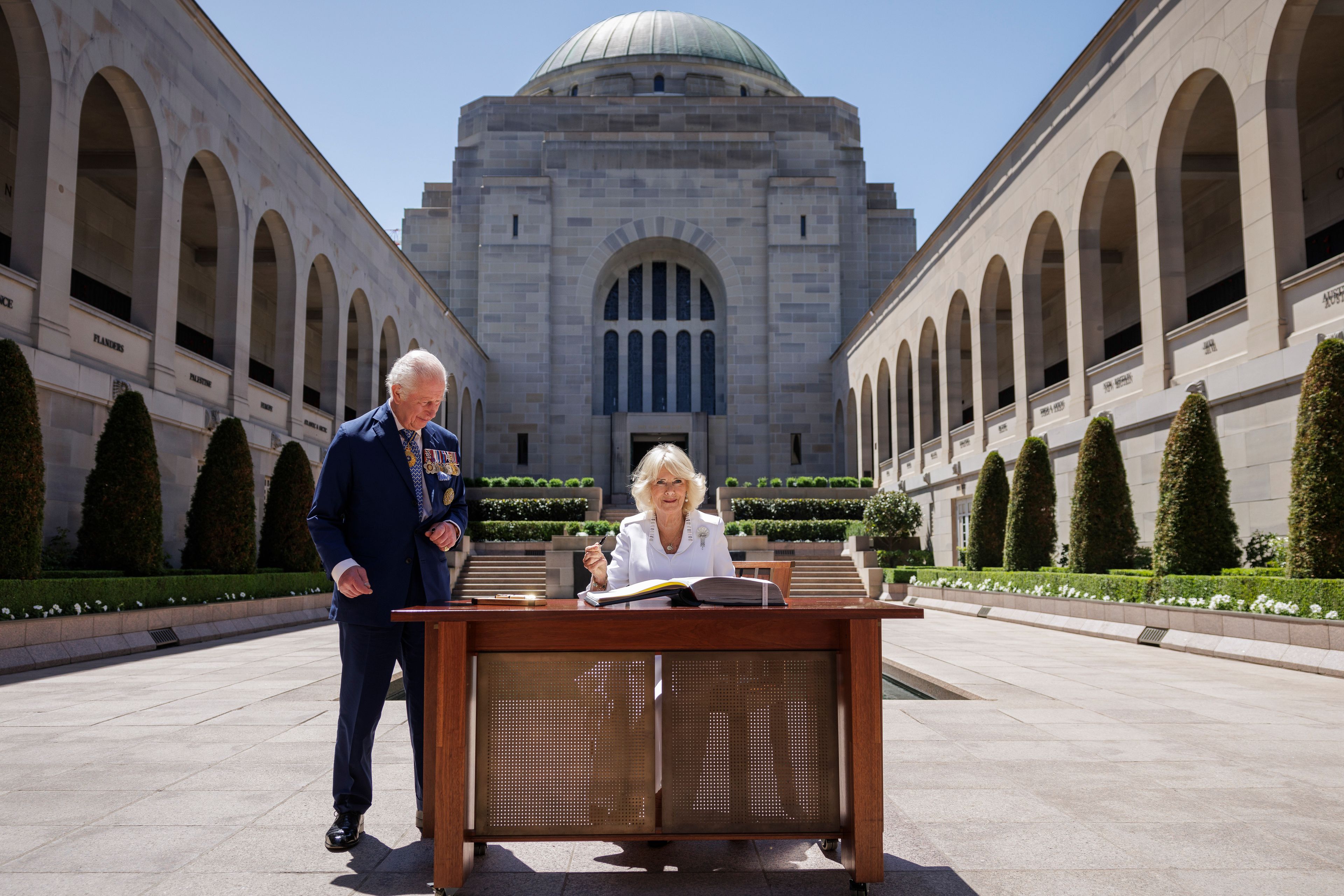 Britain's King Charles III stands next to Queen Camilla as she signs a visitor's book at the Australian War Memorial in Canberra, Australia, Monday, Oct. 21, 2024. (Brook Mitchell/Pool Photo via AP)