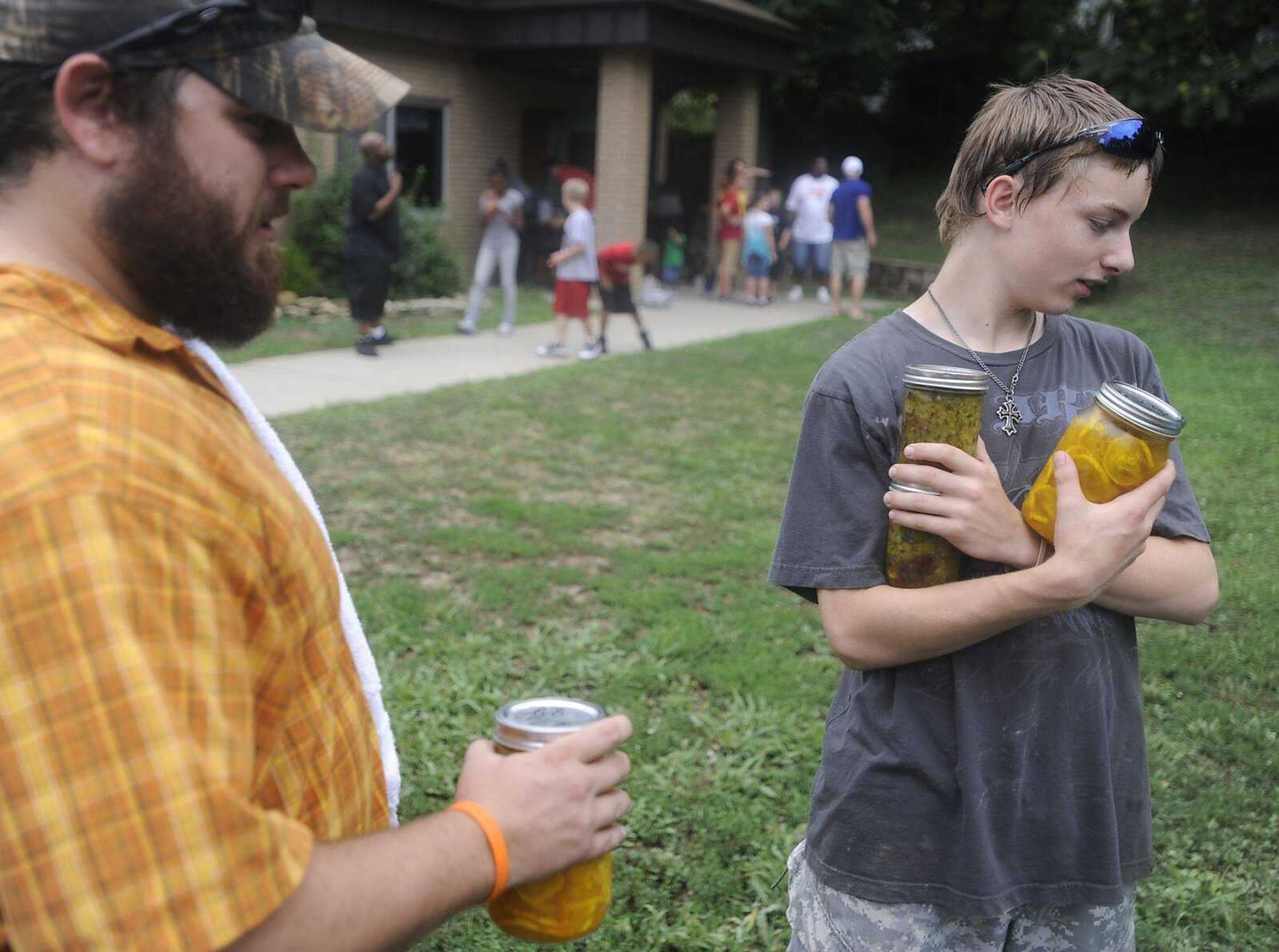 Youth Specialist Nick Cody, left, and Alan Ingram, 13, carry jars of vegetables grown and canned by fellow students July 14 at the Missouri Department of Youth Services for the Cape Girardeau facility's Family Day. (ADAM VOGLER)