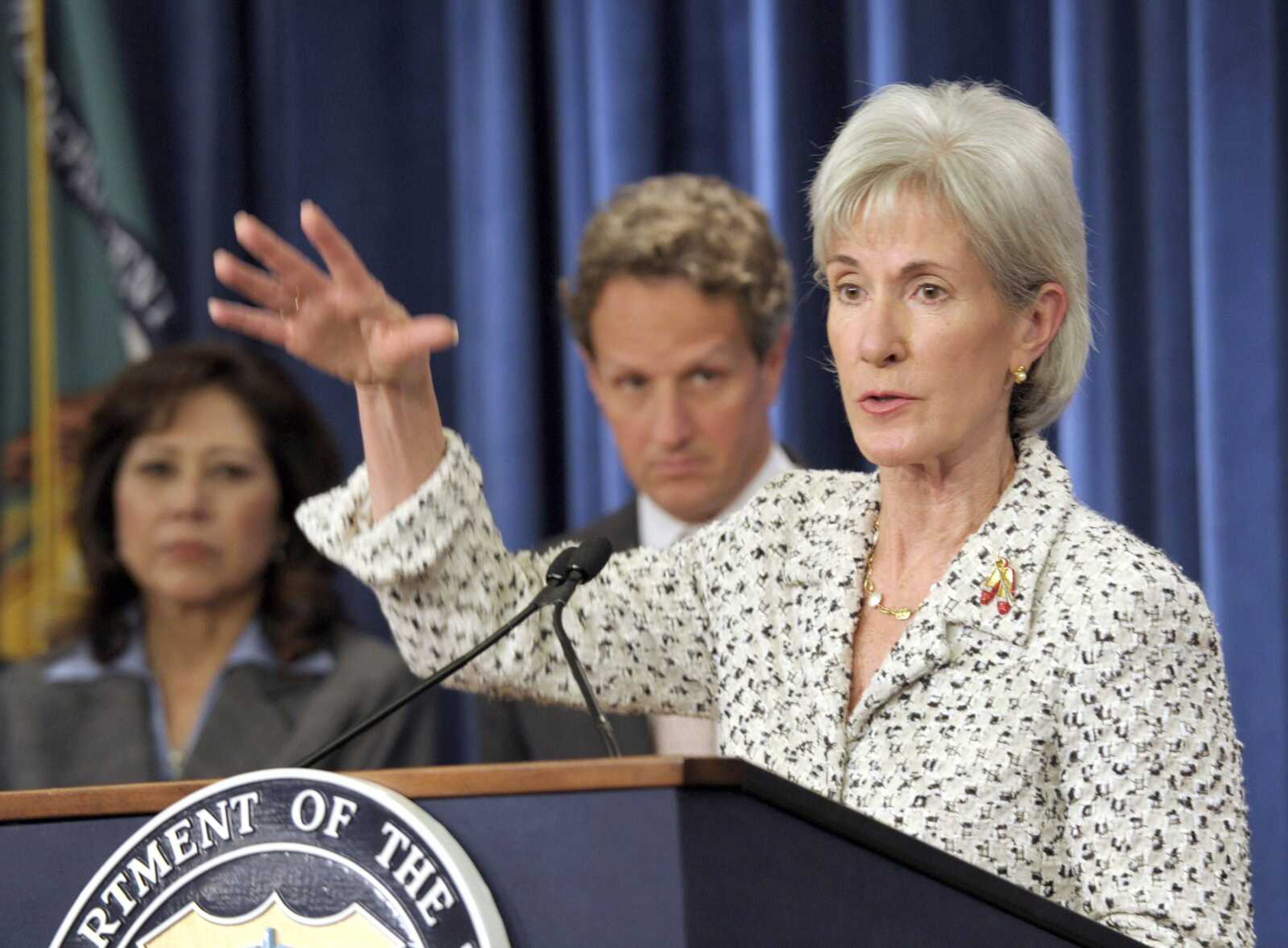 Treasury Secretary Timothy Geithner, center, and Labor Secretary Hilda Solis, left, listen Monday as Health and Human Services Secretary Kathleen Sebelius speaks at a news conference on the Social Security and Medicare Trustees Reports at the Treasury Department in Washington. (Susan Walsh ~ Associated Press)