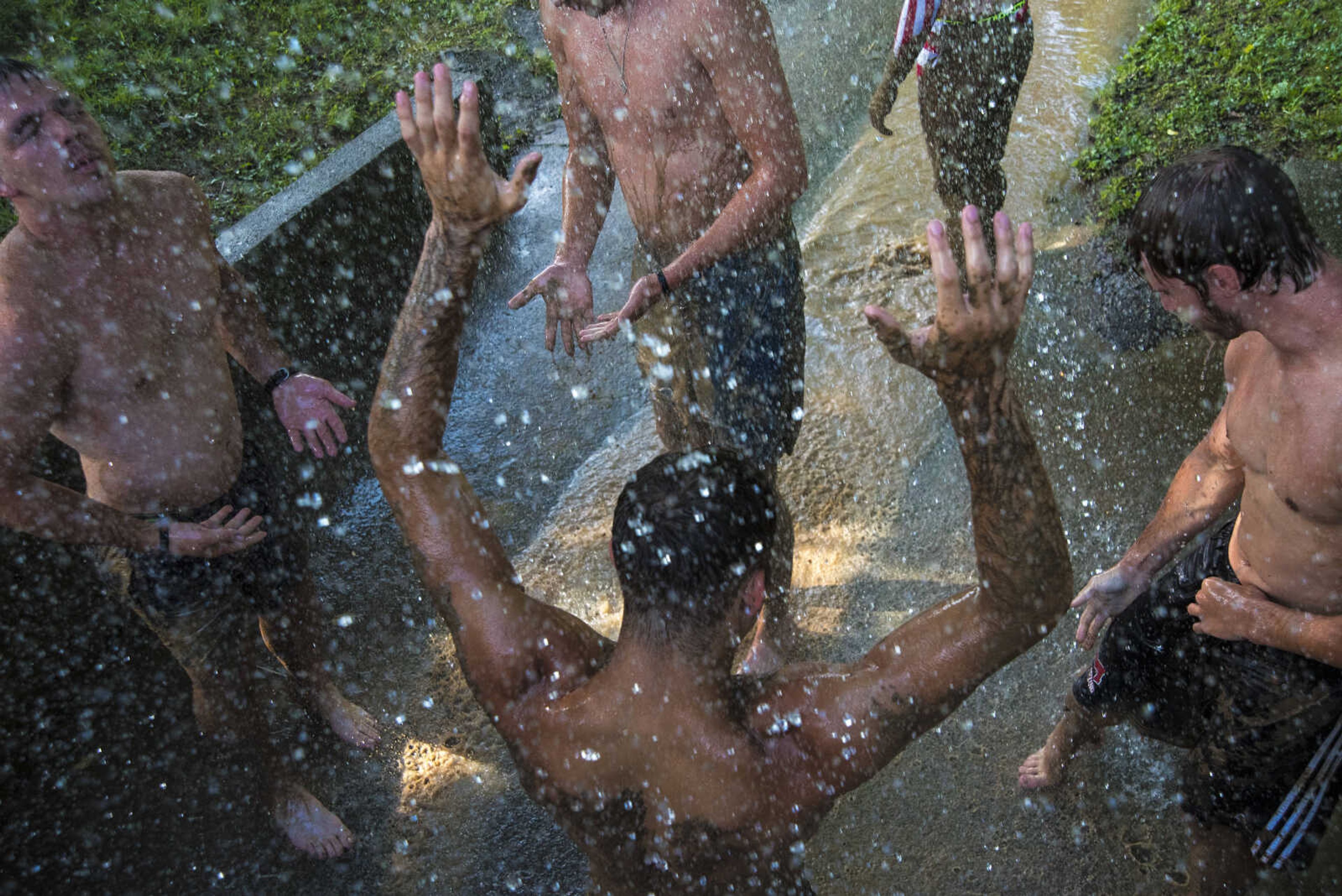 People wash off after playing mud volleyball for the Jackson Parks and Recreation's July 4th celebration Tuesday, July 4, 2017 in Jackson City Park.