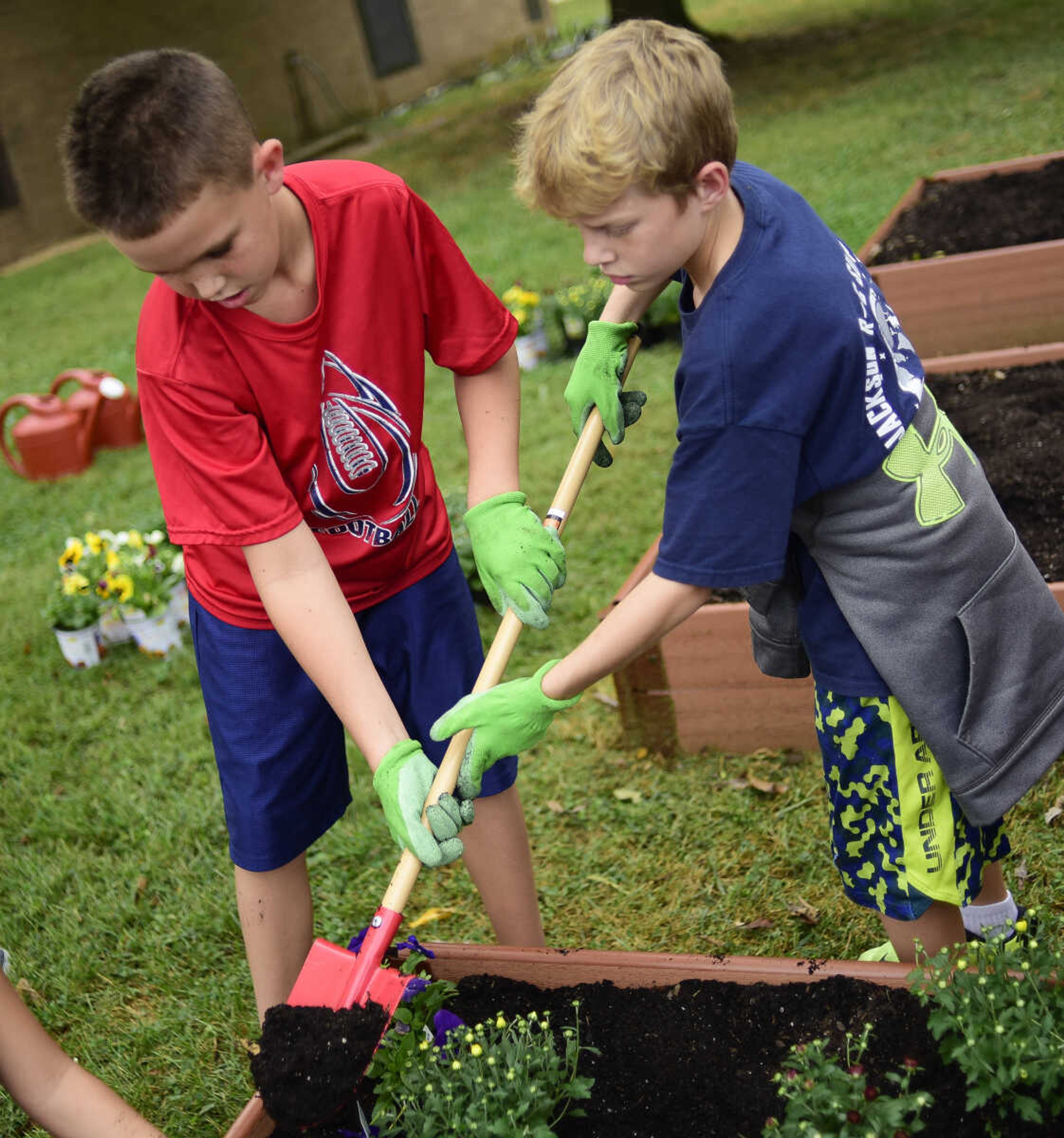 Austin Collins and Ian Harris of Mrs. Young's 5th grade class dig up dirt while they plant pansies and mums in flower beds donated by Lowe's as part of the Lowe's Heroes program Monday, Sept. 18, 2017 at West Lane Elementary in Jackson. Lowe's donated 12 flower beds, 10 picnic tables and three new benches for the school.