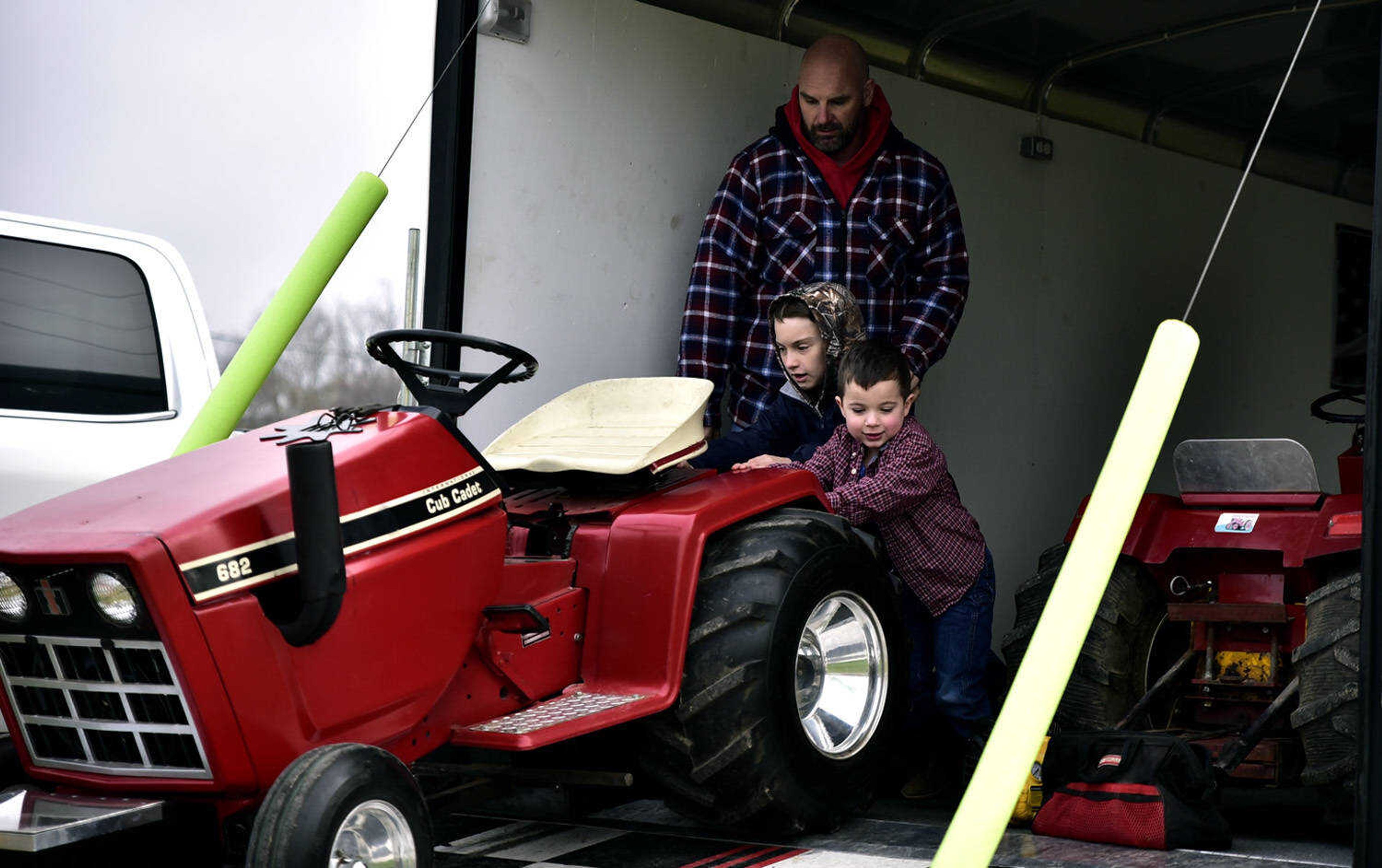 From left, Steve Eddy watches as Jaydon Eddy, 8, and Trenton Maddox, 4, push out their garden tractor out of the trailer at the Cousin Carl Farm Show on Saturday, March 10, 2018, at Arena Park in Cape Girardeau.