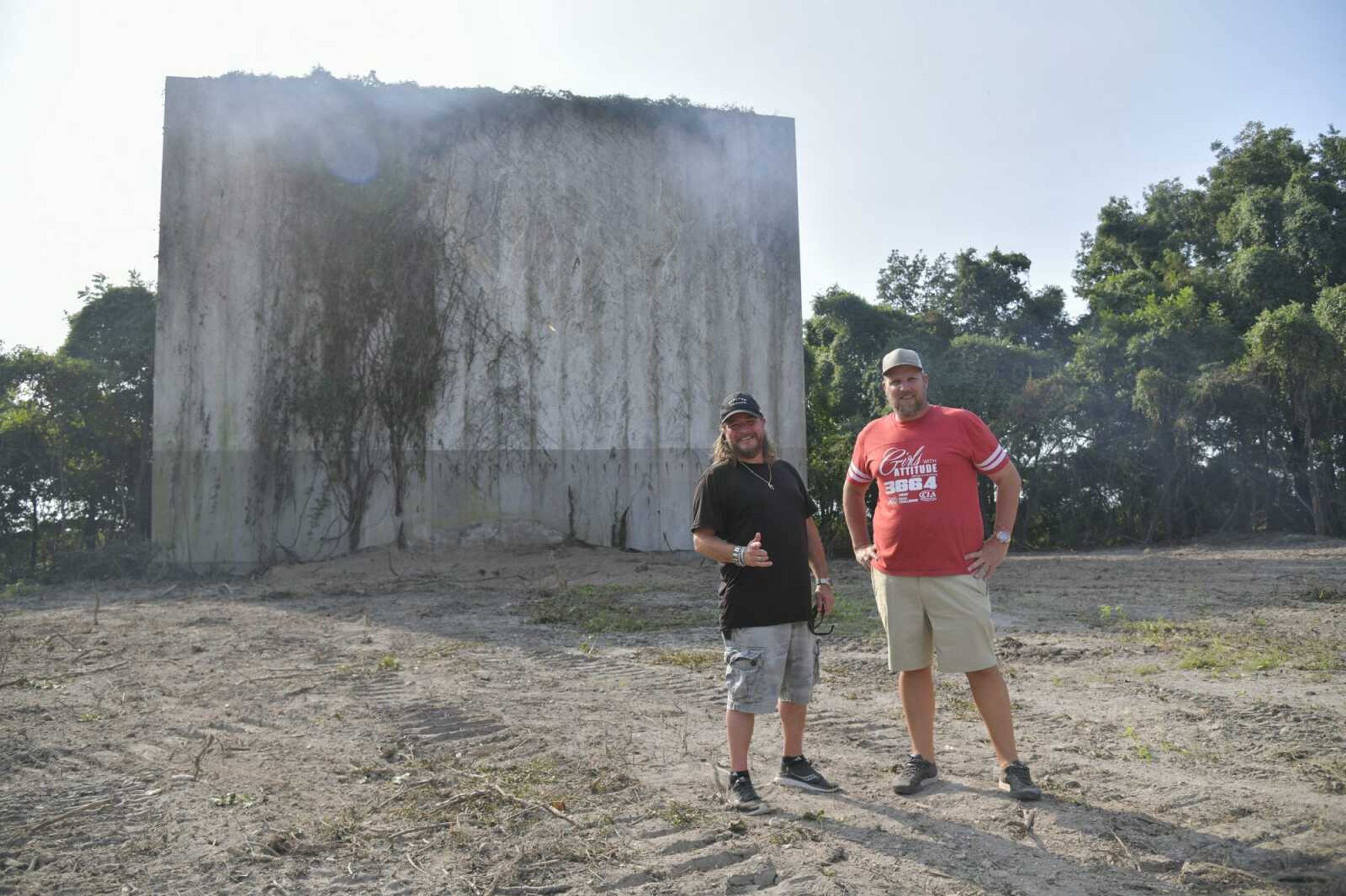 Jonny Tosarello, left, and Chuck Stratton pose for a photo in front of the concrete drive-in projection screen of the former Montgomery Drive-In in Blomeyer. The two are behind the project to create Rock 'N' Roll Drive-In on the site of an old drive-in theater that has been closed for many years.