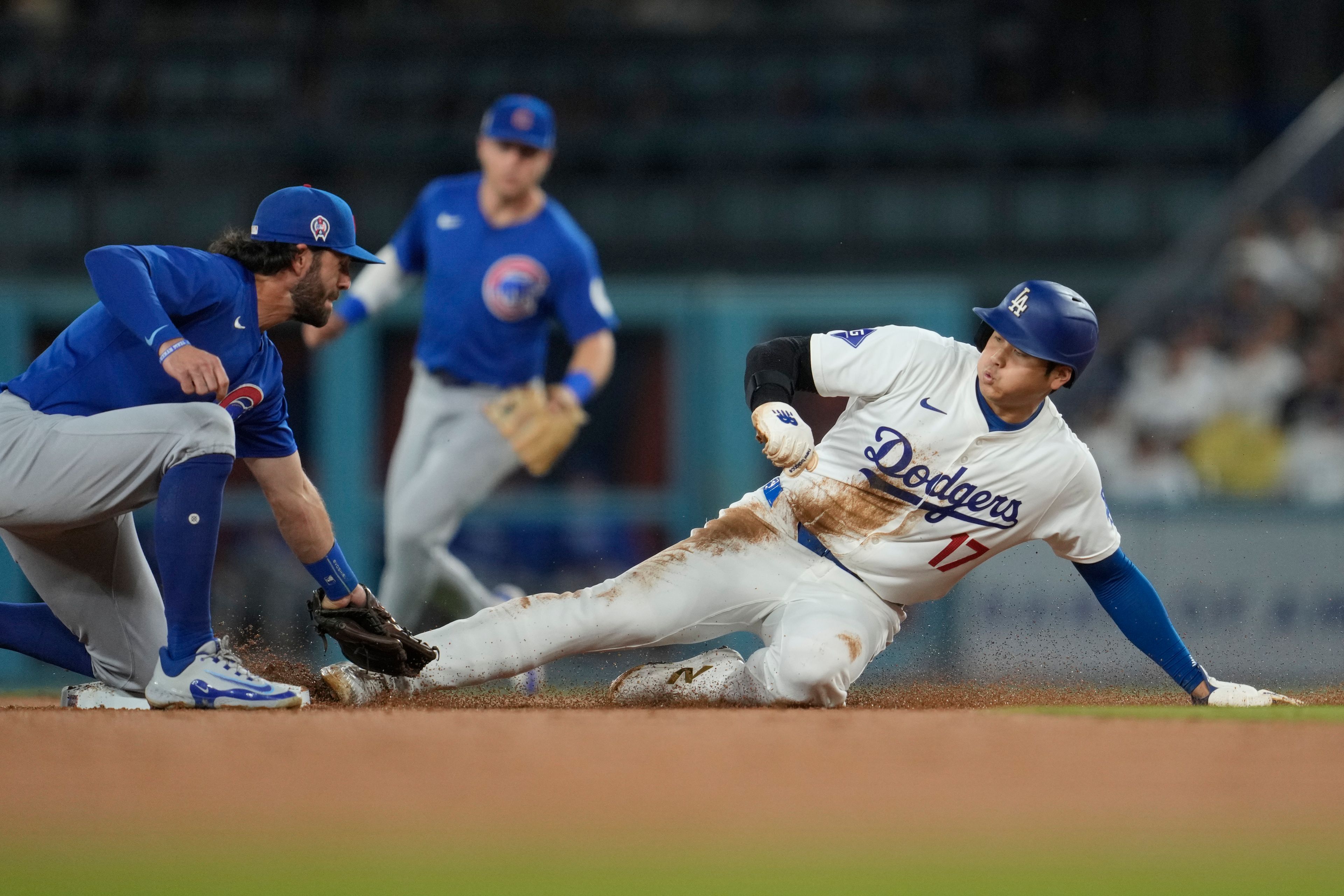 Los Angeles Dodgers designated hitter Shohei Ohtani (17) steals second base ahead of a throw to Chicago Cubs shortstop Dansby Swanson, left, during the second inning of a baseball game against the Chicago Cubs in Los Angeles, Wednesday, Sept. 11, 2024. (AP Photo/Ashley Landis)