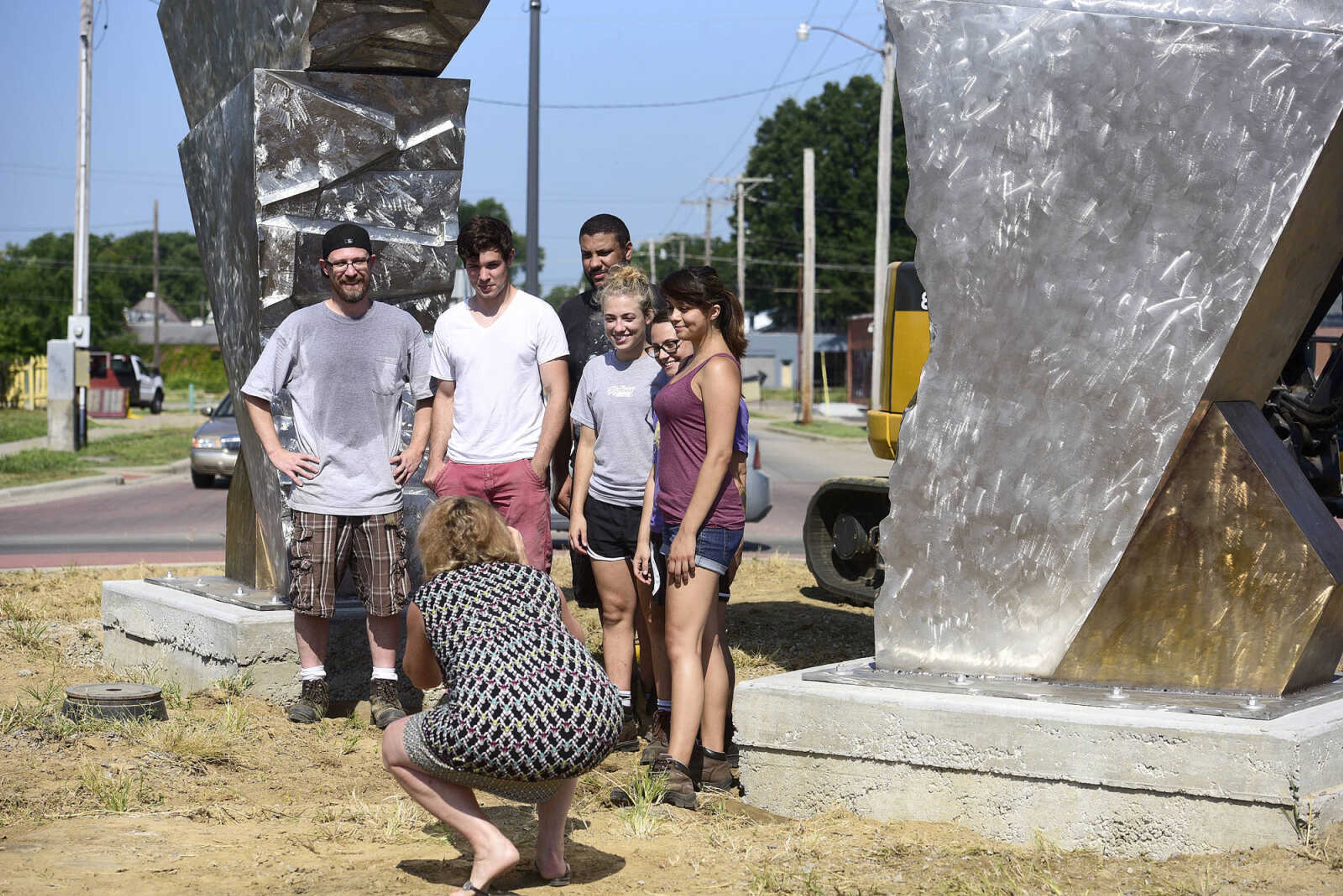 Chris Wubbena, left, poses for a picture with his current and former students, Terry Davis, Vatchae Sams, Jessica Lambert, Brigit Ciskowski and Deanna Hoffman after the installation of Wubbena's 14-foot sculpture, "Commence", in the Fountain Street roundabout on Monday, July 24, 2017, near the River Campus. The students helped build the sculpture.