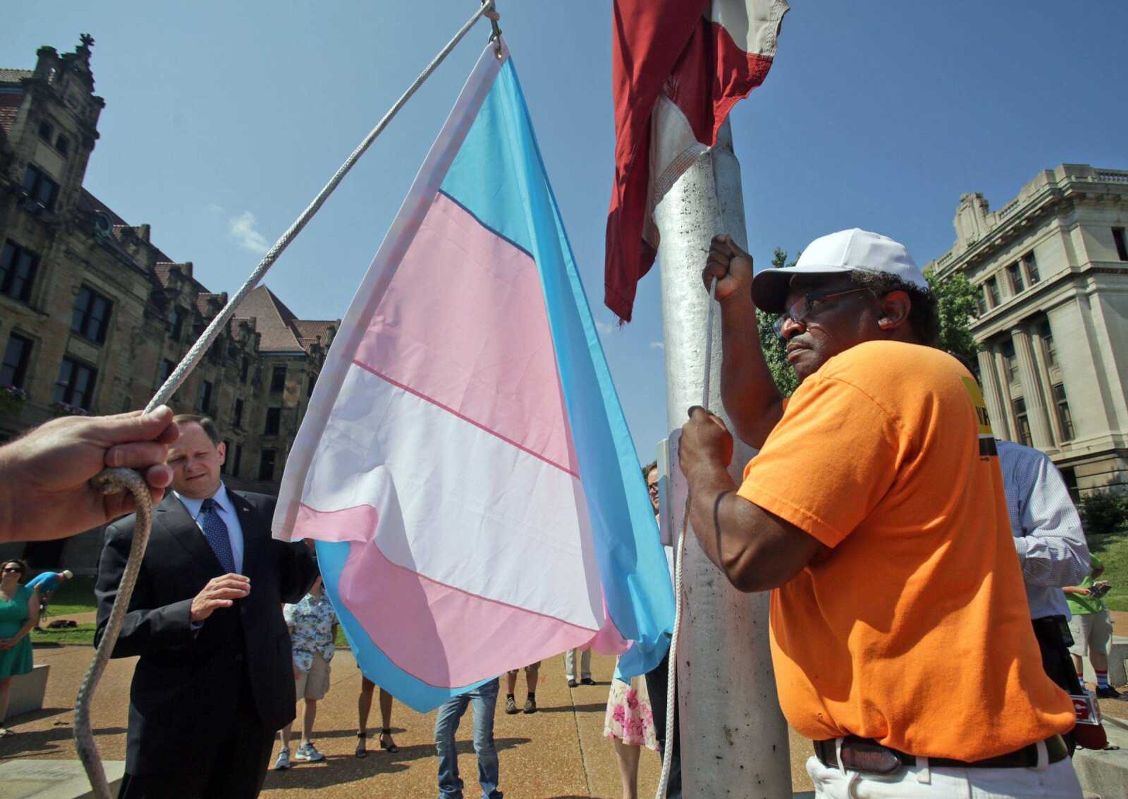 St. Louis Mayor Francis Slay, left, watches as Andre Henderson, right, raises a transgender flag Monday outside City Hall in St. Louis. Slay said the city is sending a message of inclusiveness by raising the flag.