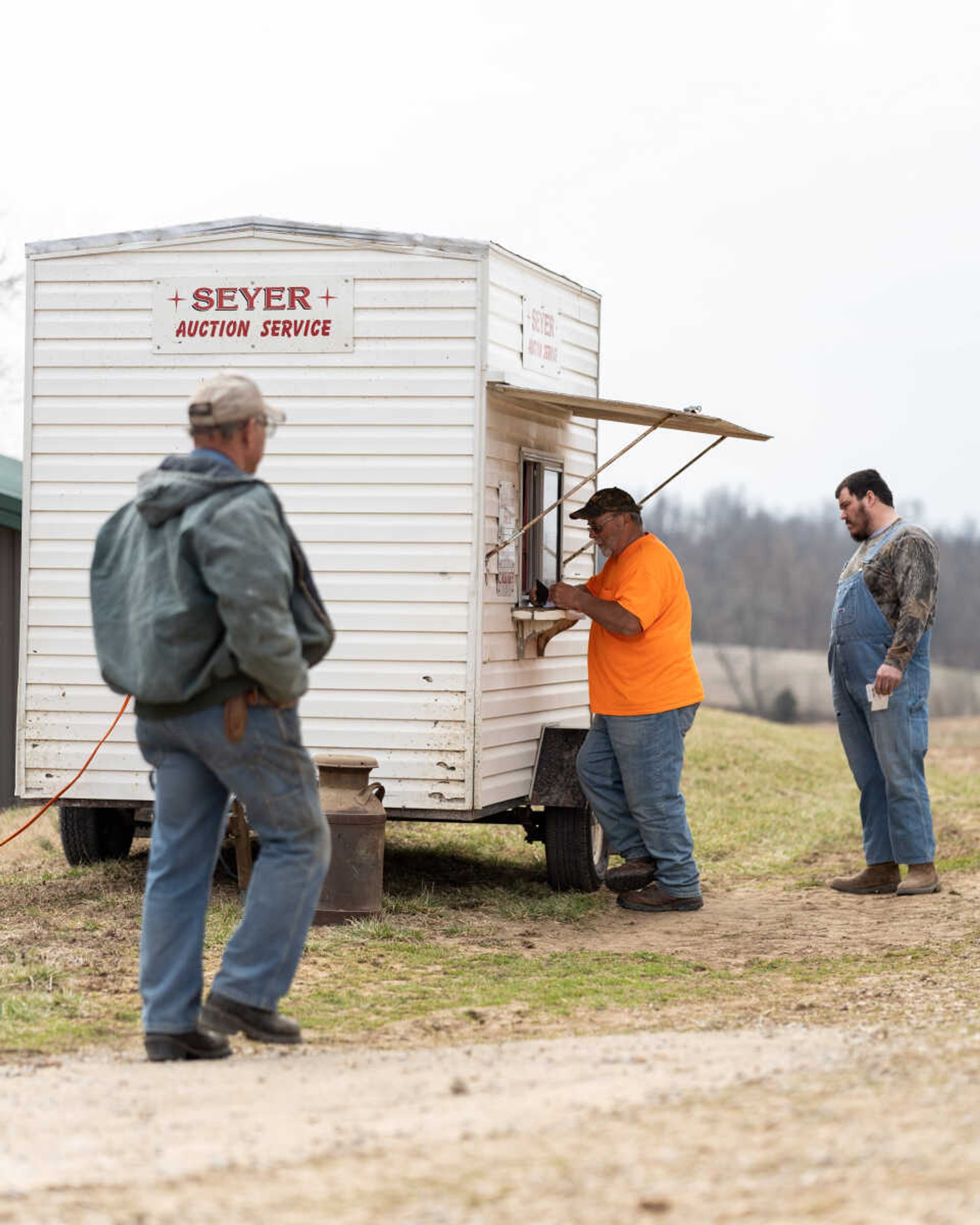 Attendees pay for the items they bid on and won at an auction in the Fruitland area on March 5, 2022. Auctioneer Charley Mangels says when he's auctioneering, he encourages people to bid on items by joking with them.