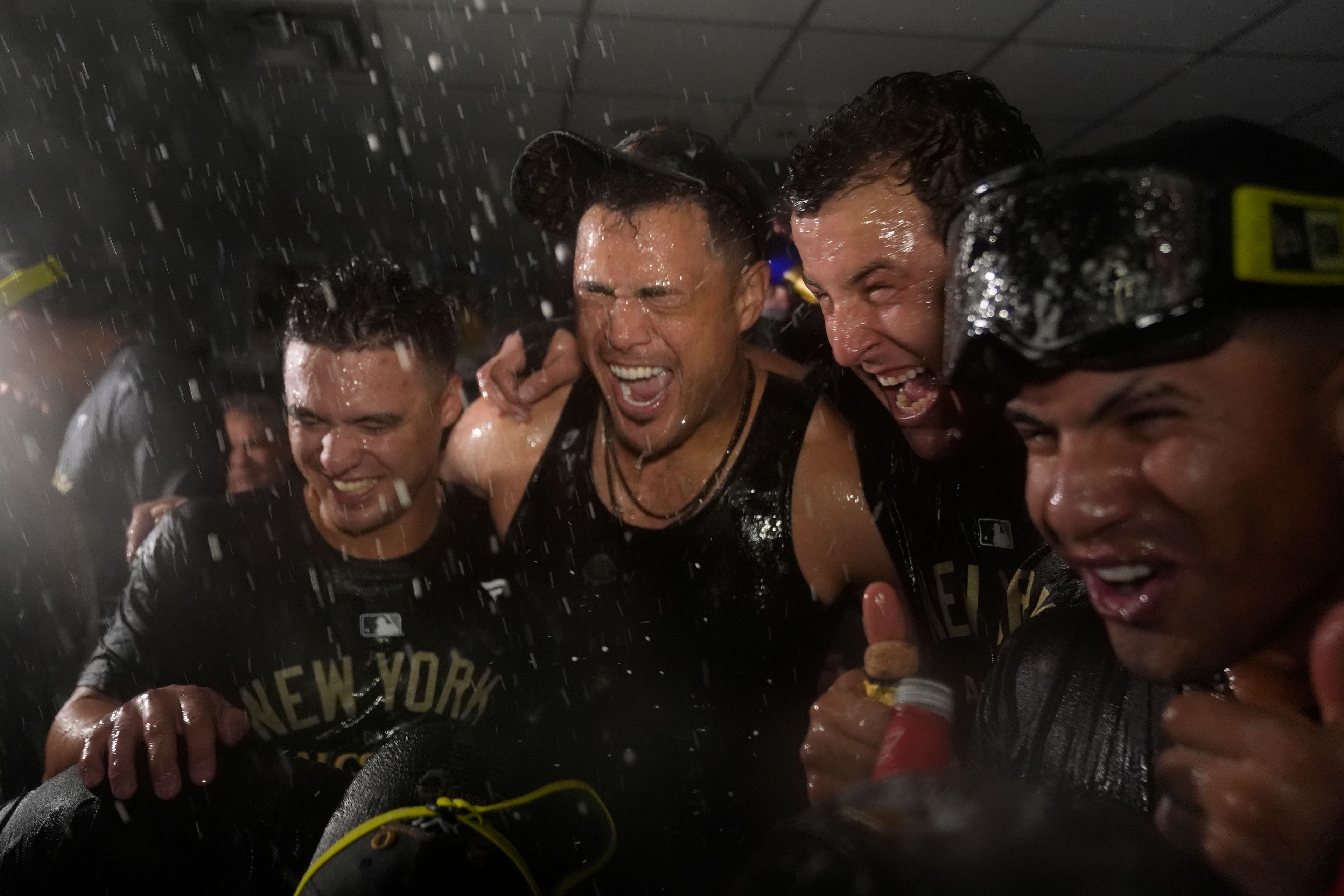 Members of the New York Yankees celebrate in the clubhouse following a 3-1 victory over the Kansas City Royals in Game 4 of an American League Division baseball playoff series Thursday, Oct. 10, 2024, in Kansas City, Mo. (AP Photo/Charlie Riedel)