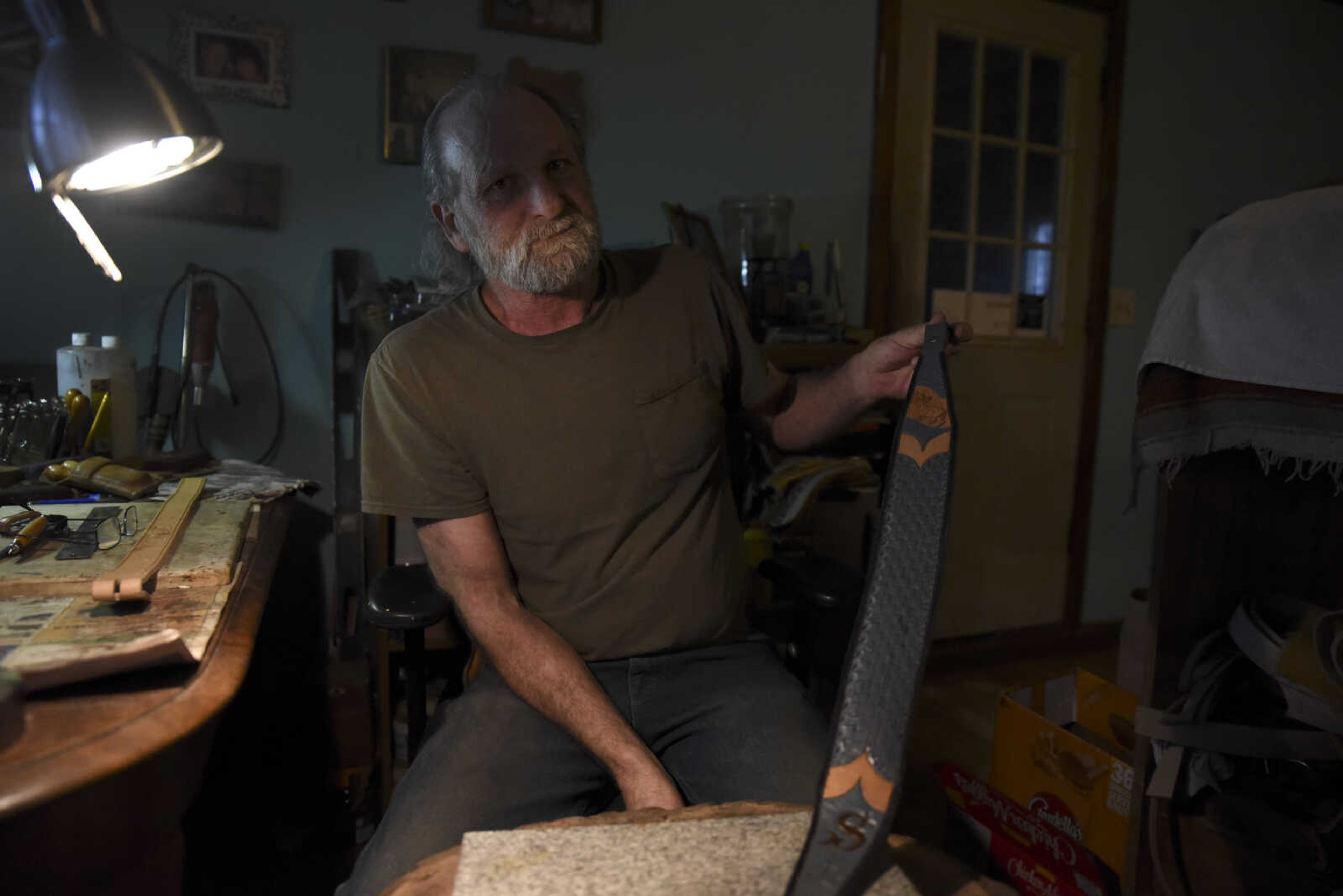 John Hedge shows a hand-made leather guitar strap in his home on Tuesday, March 27, 2018, in Advance.