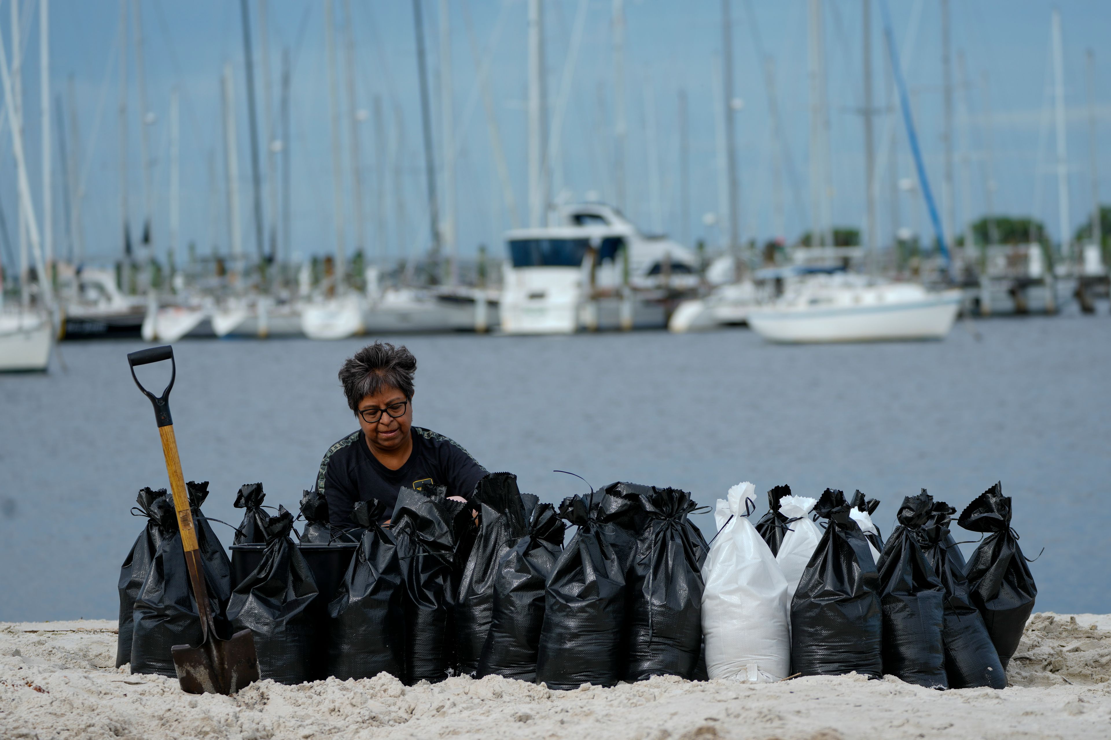 Susana Ortiz fills out sand bags on the beach at the Davis Islands Yacht Basin as she prepares for the arrival of Hurricane Milton, Tuesday, Oct. 8, 2024, in Tampa, Fla. (AP Photo/Julio Cortez)