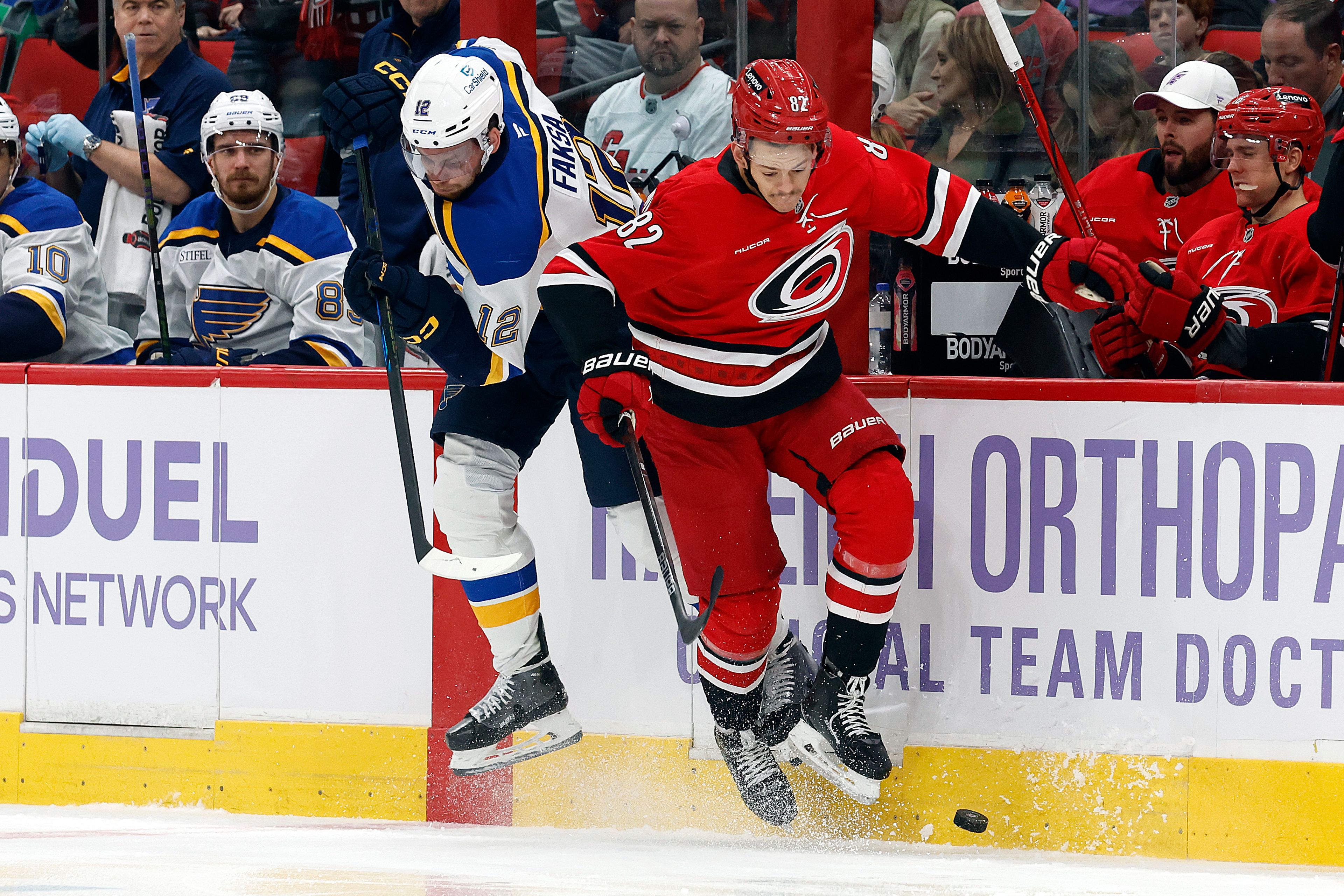 Carolina Hurricanes' Jesperi Kotkaniemi (82) collides with St. Louis Blues' Radek Faksa (12) knocking him off the puck during the first period of an NHL hockey game in Raleigh, N.C., Sunday, Nov. 17, 2024. (AP Photo/Karl B DeBlaker)