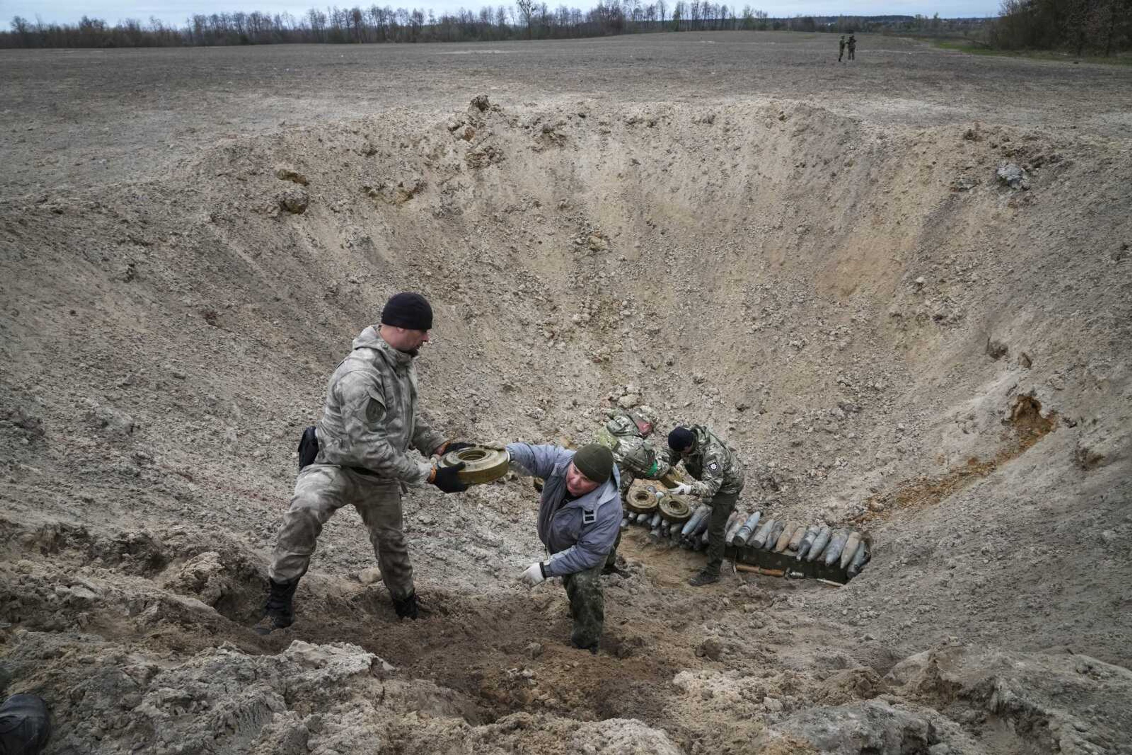 Interior ministry sappers collect explosives in a hole to detonate them near a mine field Tuesday after recent battles at the village of Moshchun close to Kyiv, Ukraine.