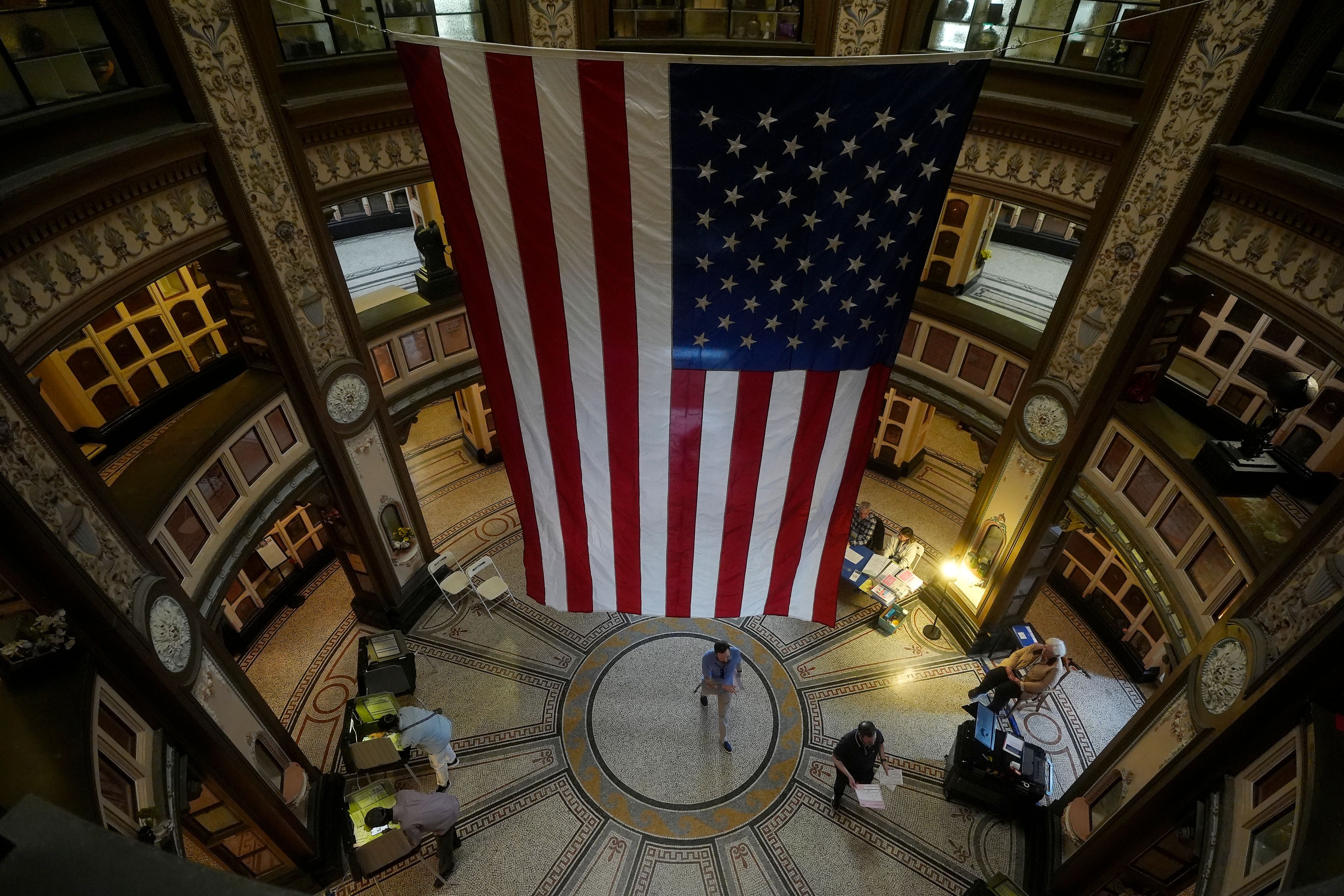 A large flag hangs from the ceiling as people vote at the San Francisco Columbarium & Funeral Home in San Francisco on Election Day, Tuesday, Nov. 5, 2024. (AP Photo/Jeff Chiu)