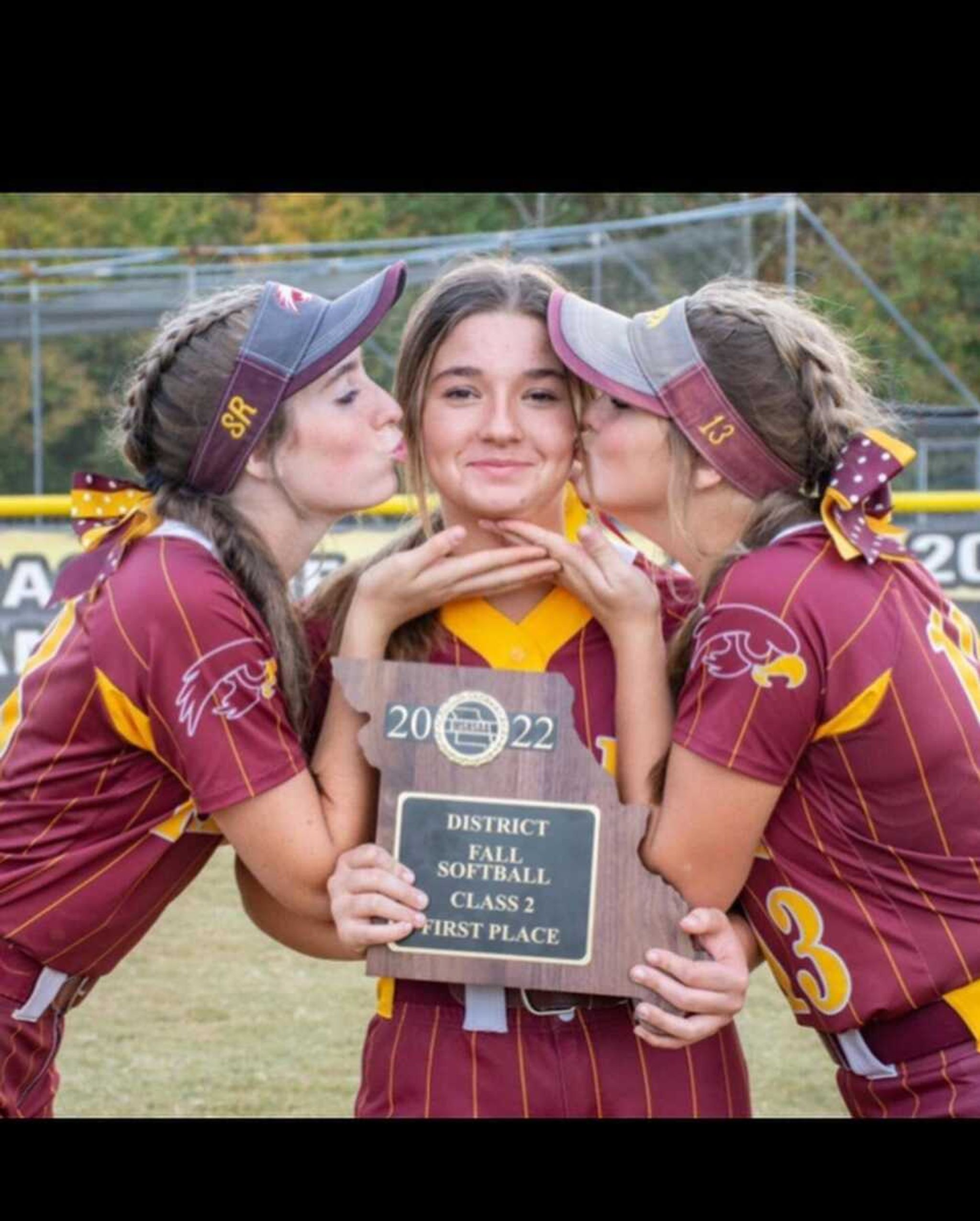 Kayleigh Holman, left, and Blaire Riley, right, kiss Cassie Gosche after the Kelly Lady Hawks won the 2022 MSHSAA Class 2 District 1 championship in 2022. Cassie suffered extensive injuries to her right arm and hand in a July vehicle crash. She hopes to return to the softball diamond next year.