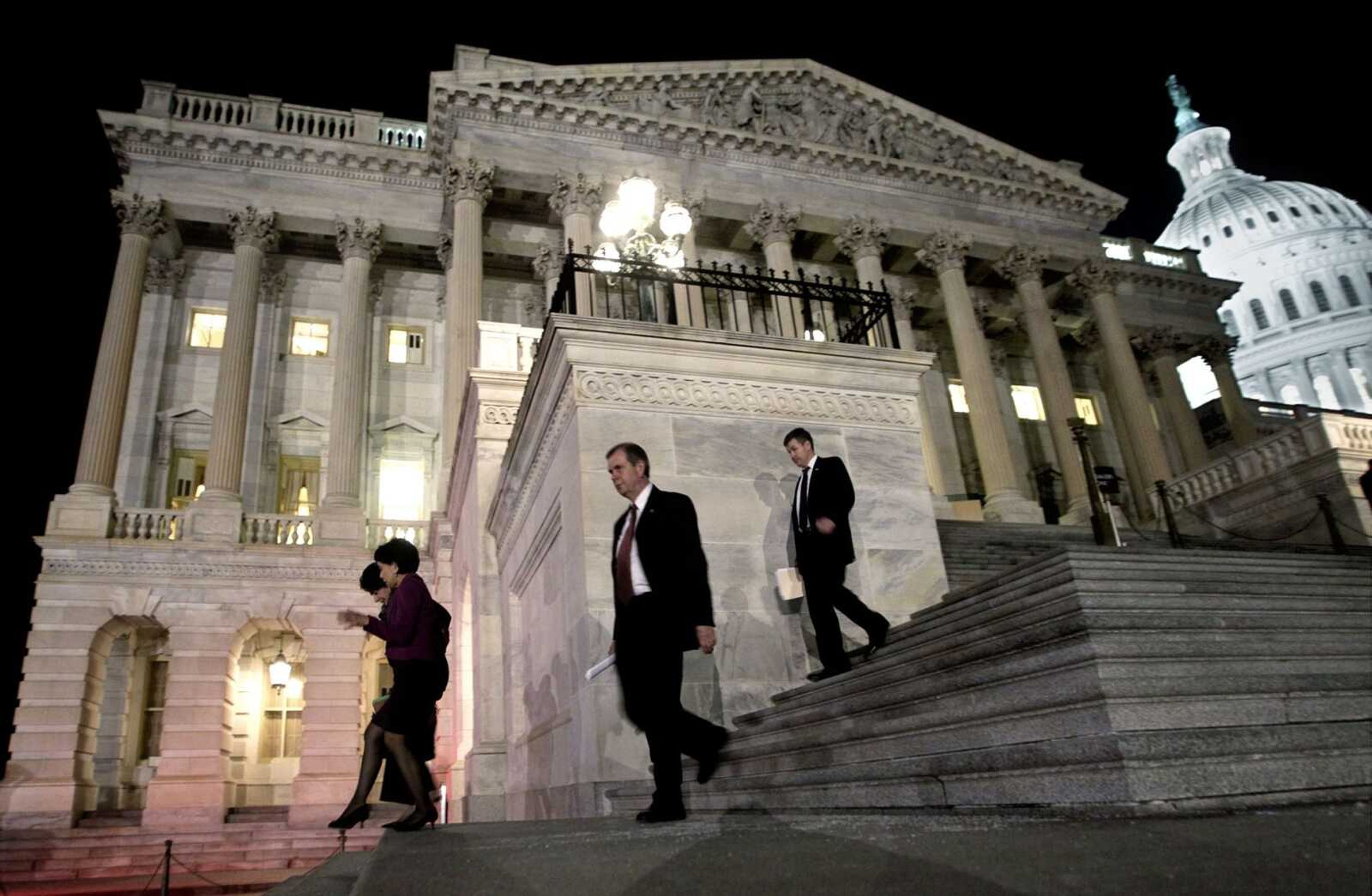 Congressmen walk down the steps of the House of Representatives in Washington as they work throughout Friday night on a spending bill. The bill was passed early Saturday. (J. Scott Applewhite ~ Associated Press)