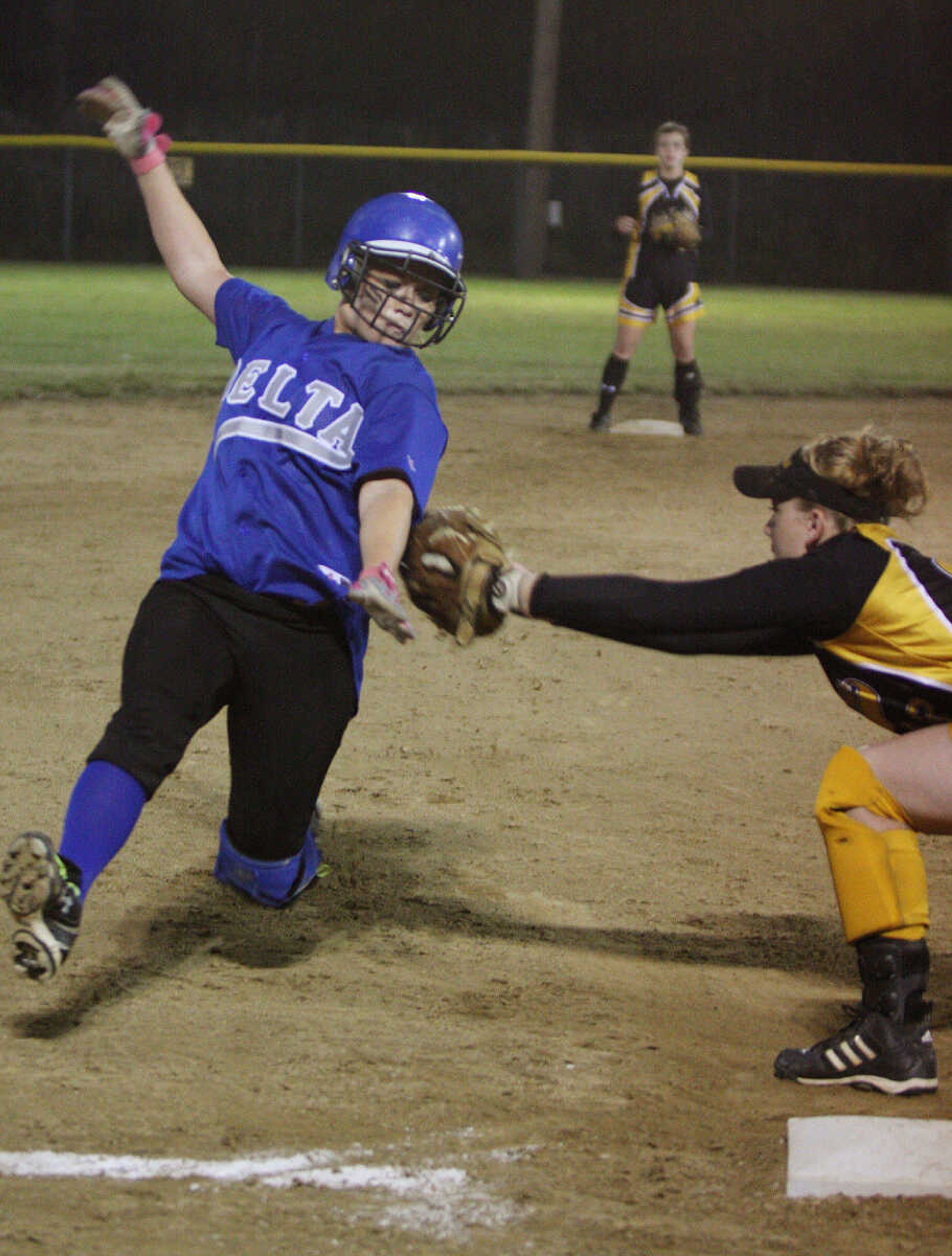 Kendra Burnett is tagged out by Moriah Goodrum while sliding into third base during the district championship game between Delta and Naylor.