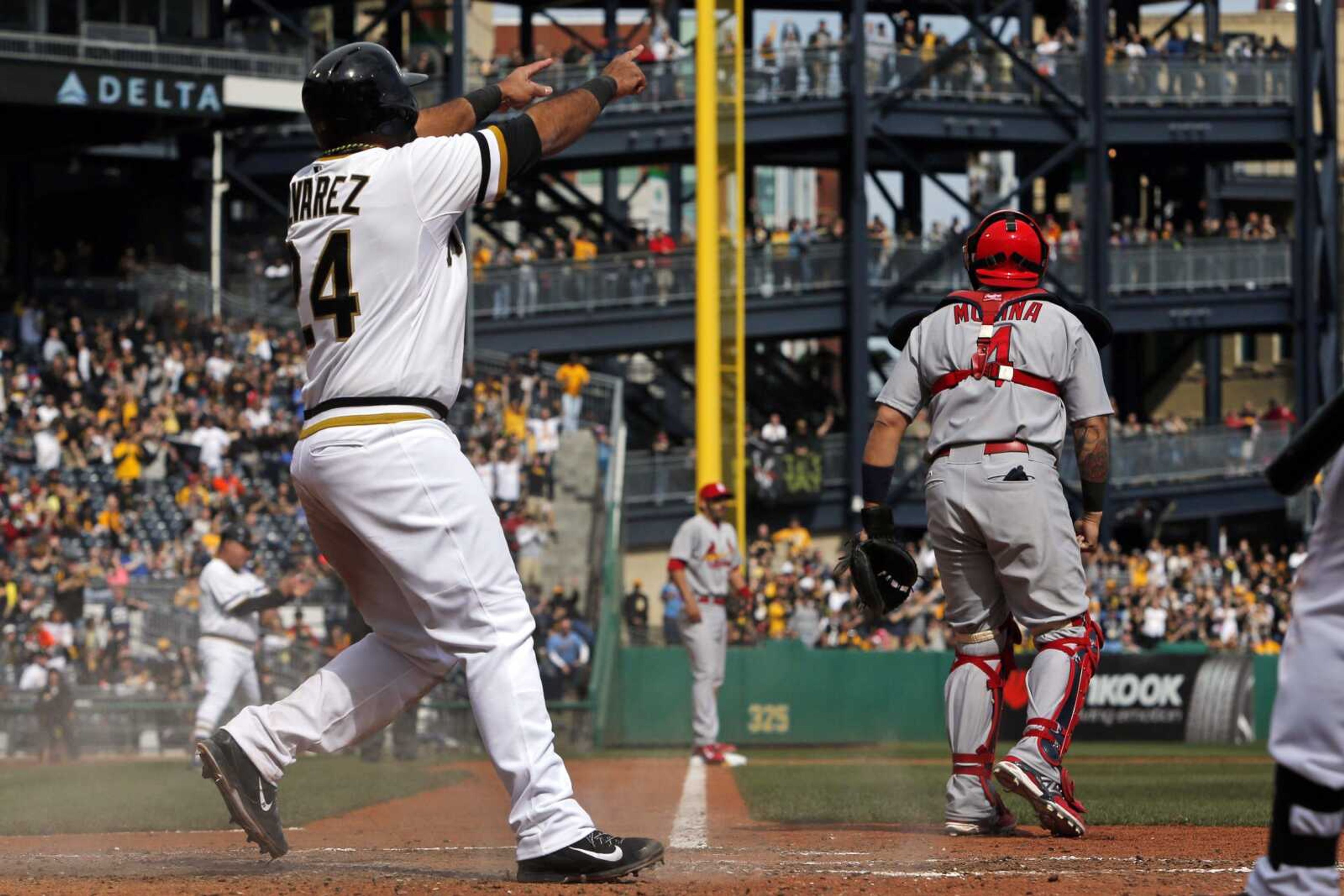 Pittsburgh Pirates' Pedro Alvarez (24) points to teammate Tony Sanchez on second base after scoring on a Sanchez double off St. Louis Cardinals starting pitcher Adam Wainwright during the seventh inning of a baseball game in Pittsburgh, Sunday, April 6, 2014. The Pirates won 2-1. (AP Photo/Gene J. Puskar)