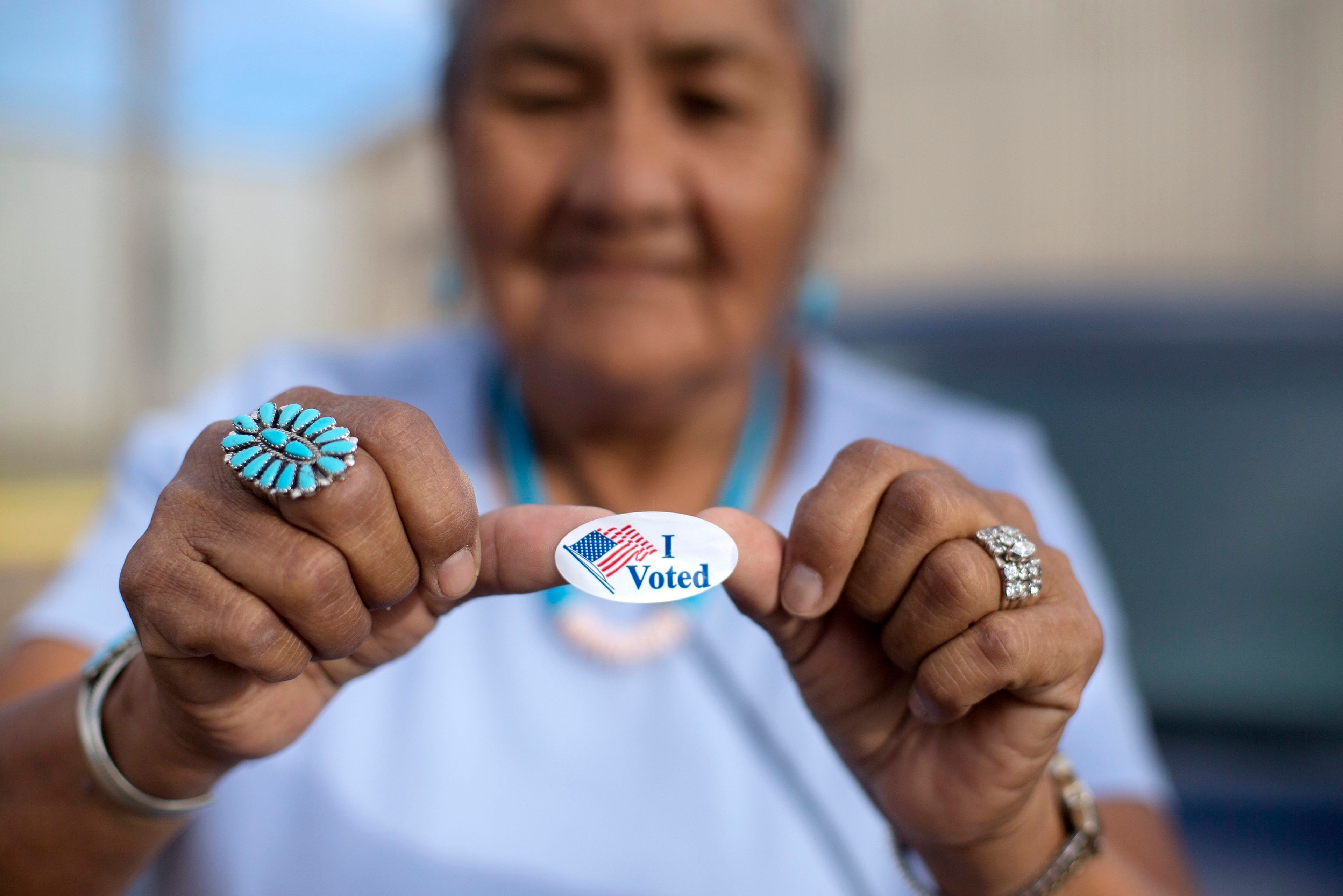 FILE - Mildred James of Sanders, Ariz., shows off her "I Voted" sticker as she waits for results of the Navajo Nation presidential primary election to be revealed in Window Rock, Ariz., Aug. 28, 2018. (AP Photo/Cayla Nimmo, File)