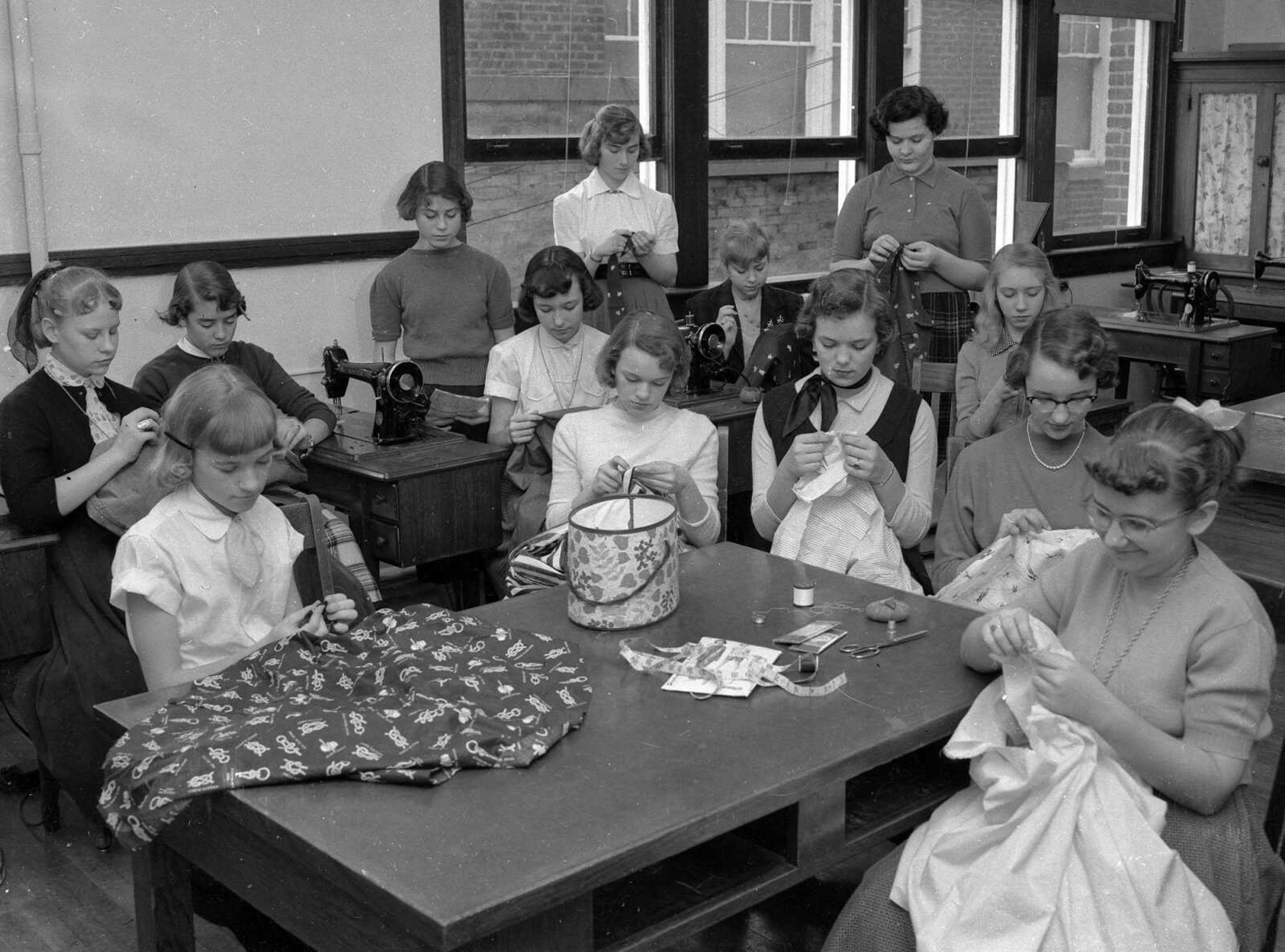 March 7, 1956 Southeast Missourian.
Future homemakers. These girls in the 8A class at Central Junior High learn, under the direction of Mrs. Glenda Marshall, the first steps in making their own clothes. Here they are busy with dresses, pajamas and Bermuda shorts. From the left, at foreground table, are Sally Allen, Sharon Smith, Judy Crabb, Kay Cook and Sarah Sullivan. At the back, Sharon Wieser, Jeane Pratte, Katie Hogenmiller, Ruth Young, Patsy Niswonger, Julia Vandivort, Mona Dougan and Peggy Phillips. (G.D. Fronabarger/Southeast Missourian archive)