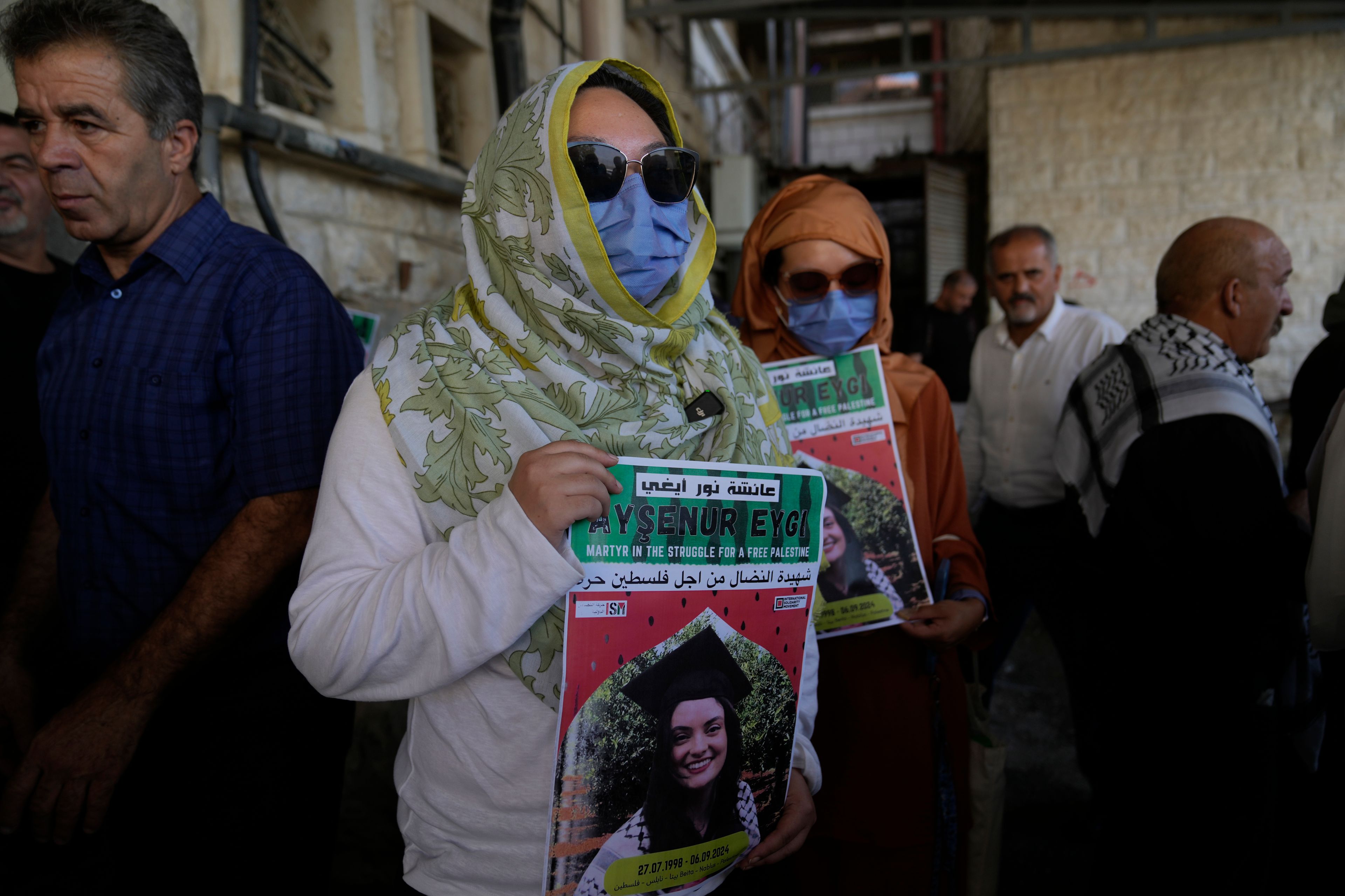 ADDS WITNESS SAYS: Two fellow activists of Aysenur Ezgi Eygi, 26, who a witness says was fatally shot by Israeli soldiers while participating in an anti-settlement protest in the West Bank, carry posters with her name and photo during Eygi's funeral procession in the West Bank city of Nablus, Monday, Sept. 9, 2024. (AP Photo/Nasser Nasser)