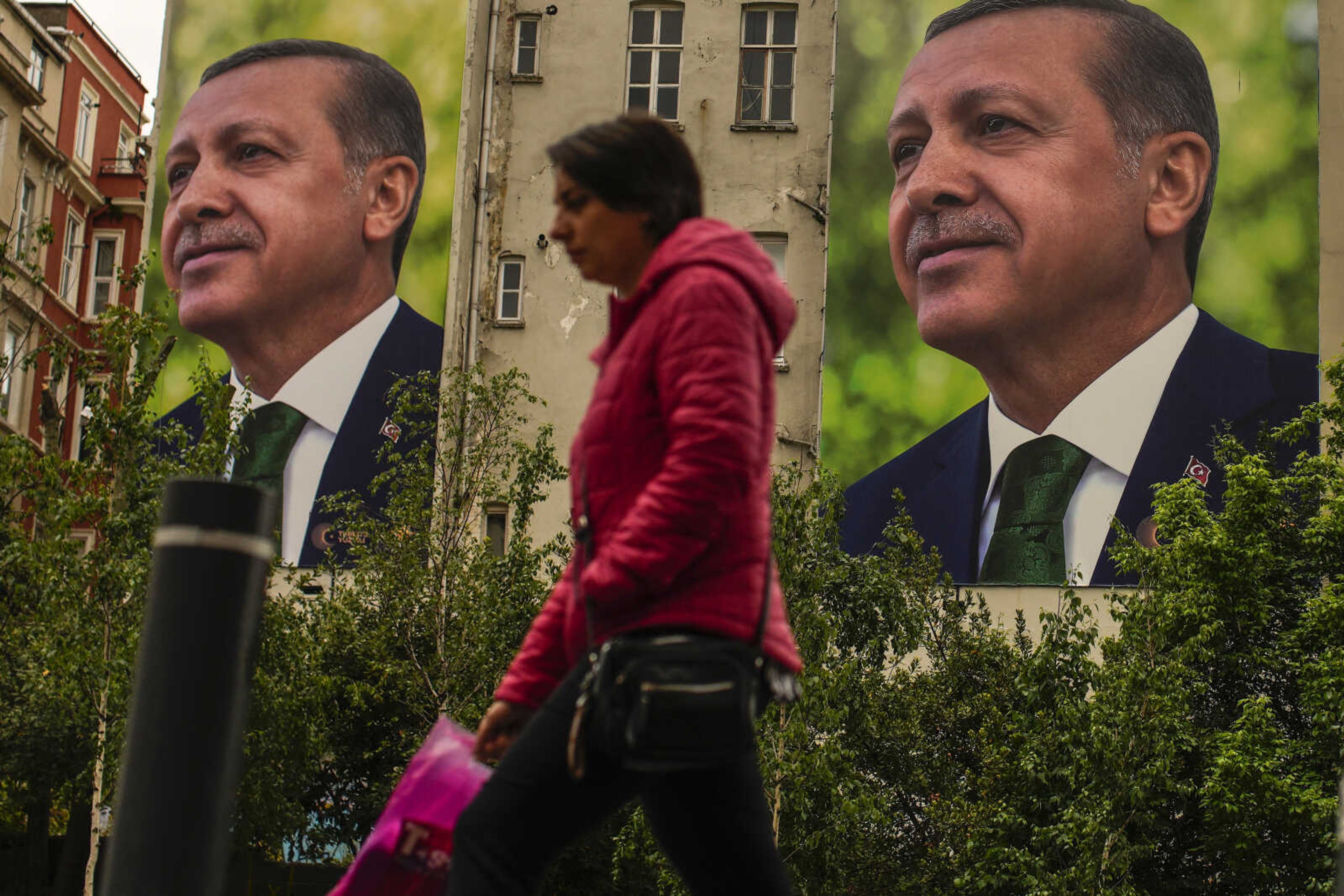 A person walks past billboards of Turkish President and People's Alliance's presidential candidate Recep Tayyip Erdogan on Monday, a day after the presidential election day, in Istanbul, Turkey. Turkey's presidential elections appeared to be heading toward a second-round runoff Monday, with Erdogan, who has ruled his country with a firm grip for 20 years, leading over his chief challenger, but falling short of the votes needed for an outright win.