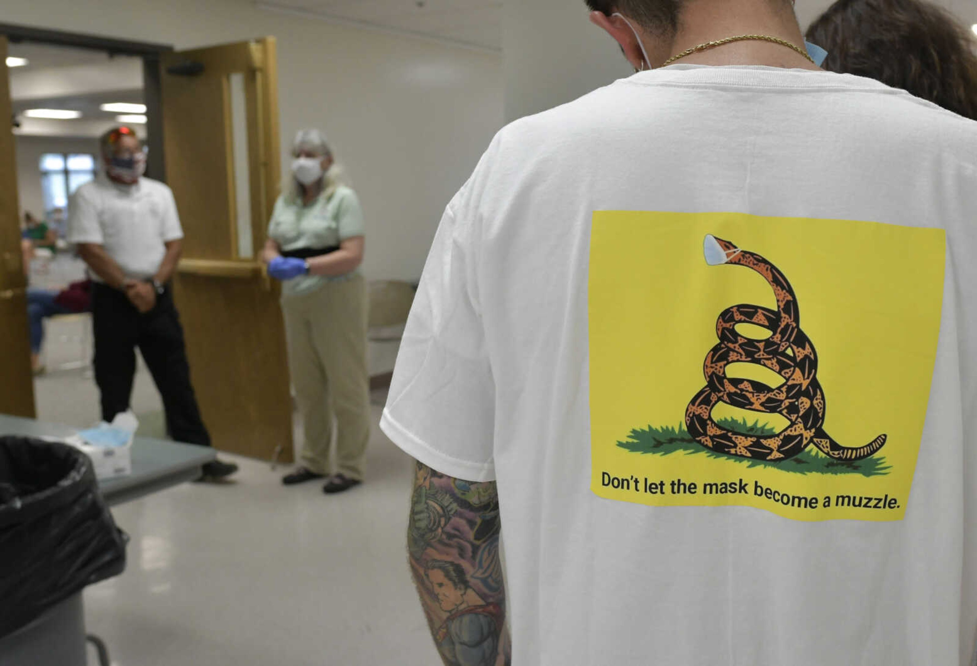 An umasked group stands outside of a Cape Girardeau County Public Health Center Board of Trustees meeting as officials stand near a sign-in form at the doorway Tuesday, July 28, 2020, at the Osage Centre in Cape Girardeau.