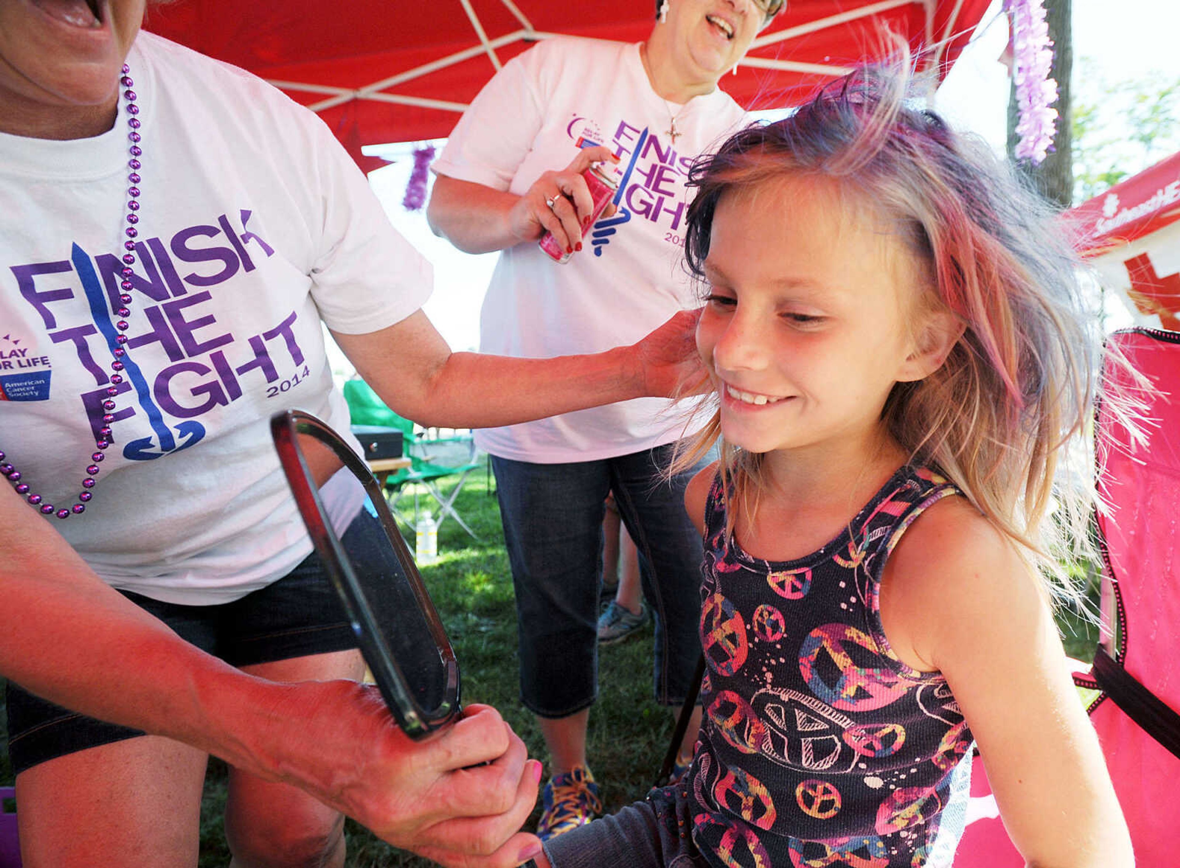 LAURA SIMON ~ lsimon@semissourian.com

Lisa Hemman, left, and Tammy Bohnert, center, put the finishing touches on Trinity Vandeven's new pink and blue hair style, Saturday, June 14, 2014, during the Relay for Life of Cape Girardeau County fundraiser at Arena Park.