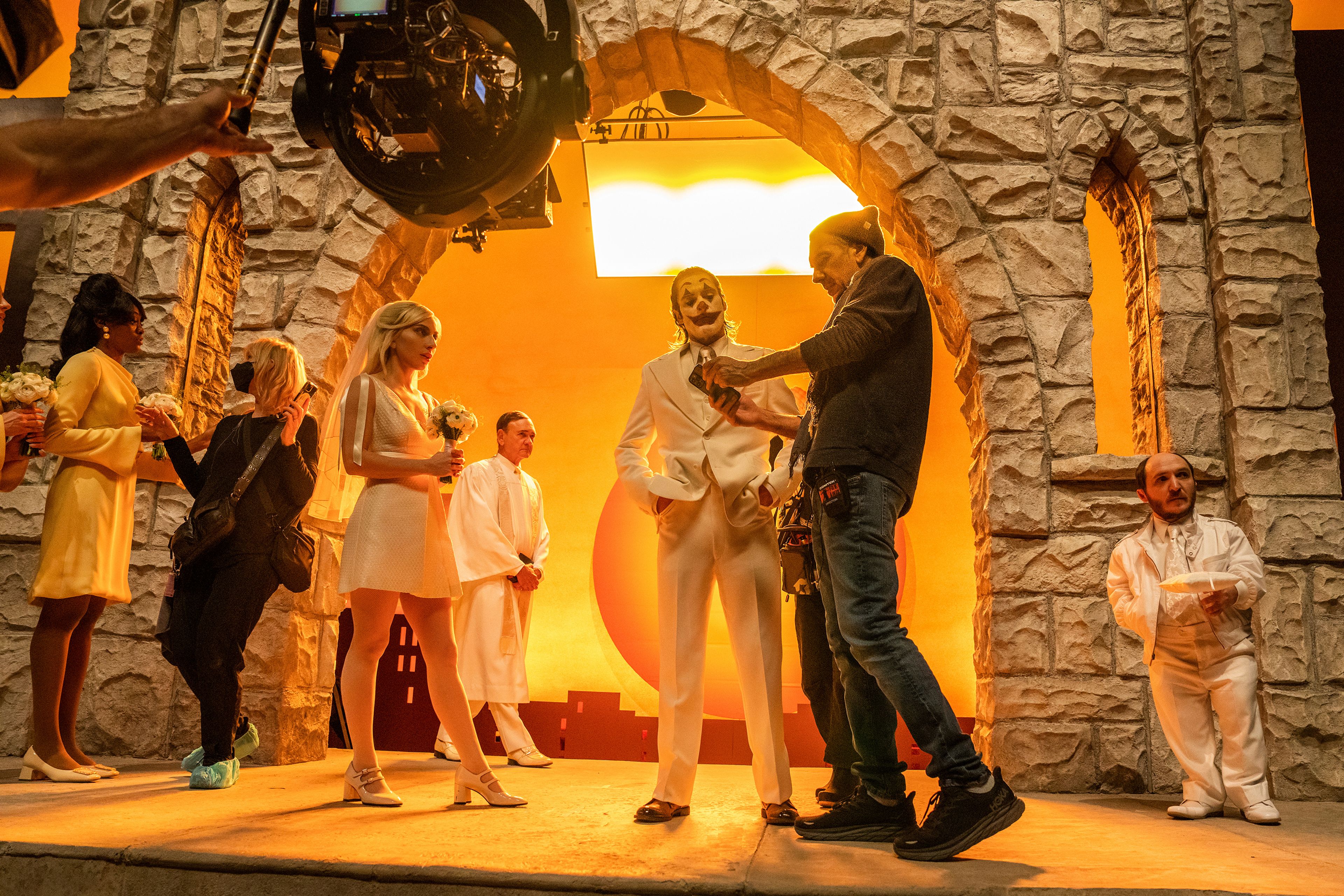 This image released by Warner Bros. Pictures shows actors Lady Gaga, left, and Joaquin Phoenix, center, on the set with filmmaker Todd Phillips during the filming of "Joker: Folie à Deux." (Niko Tavernise/Warner Bros. Pictures via AP)