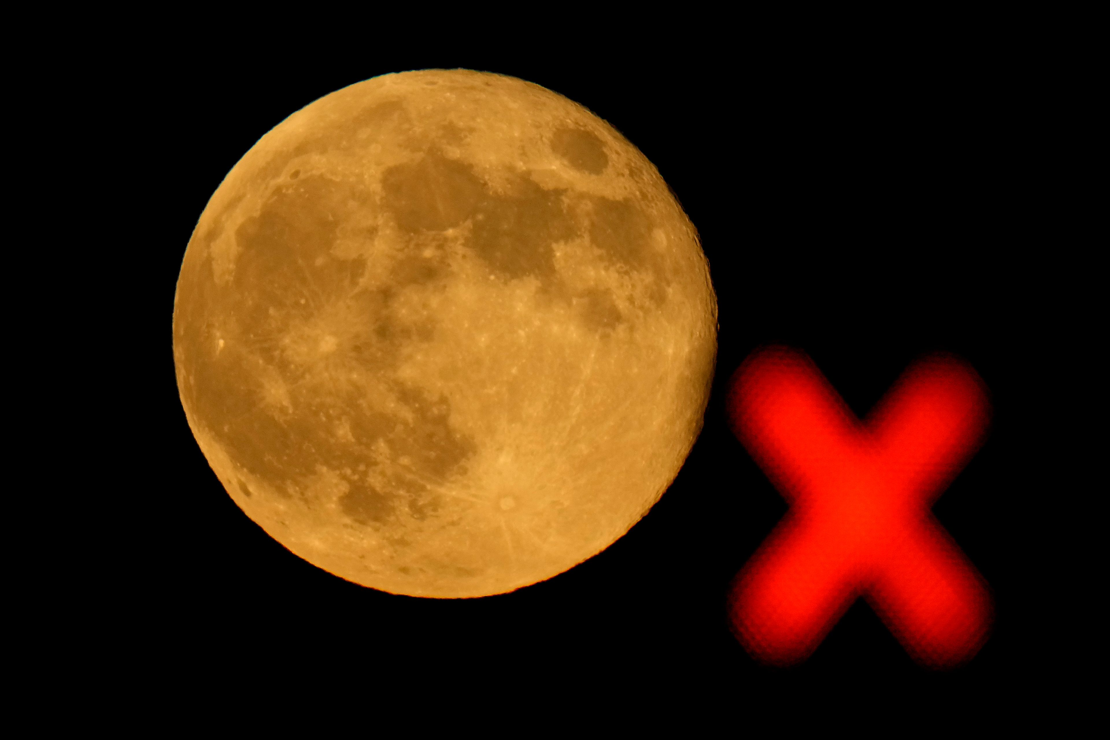 The waning supermoon rises beyond a train signal Thursday, Oct. 17, 2024, in Lenexa, Kan. (AP Photo/Charlie Riedel)