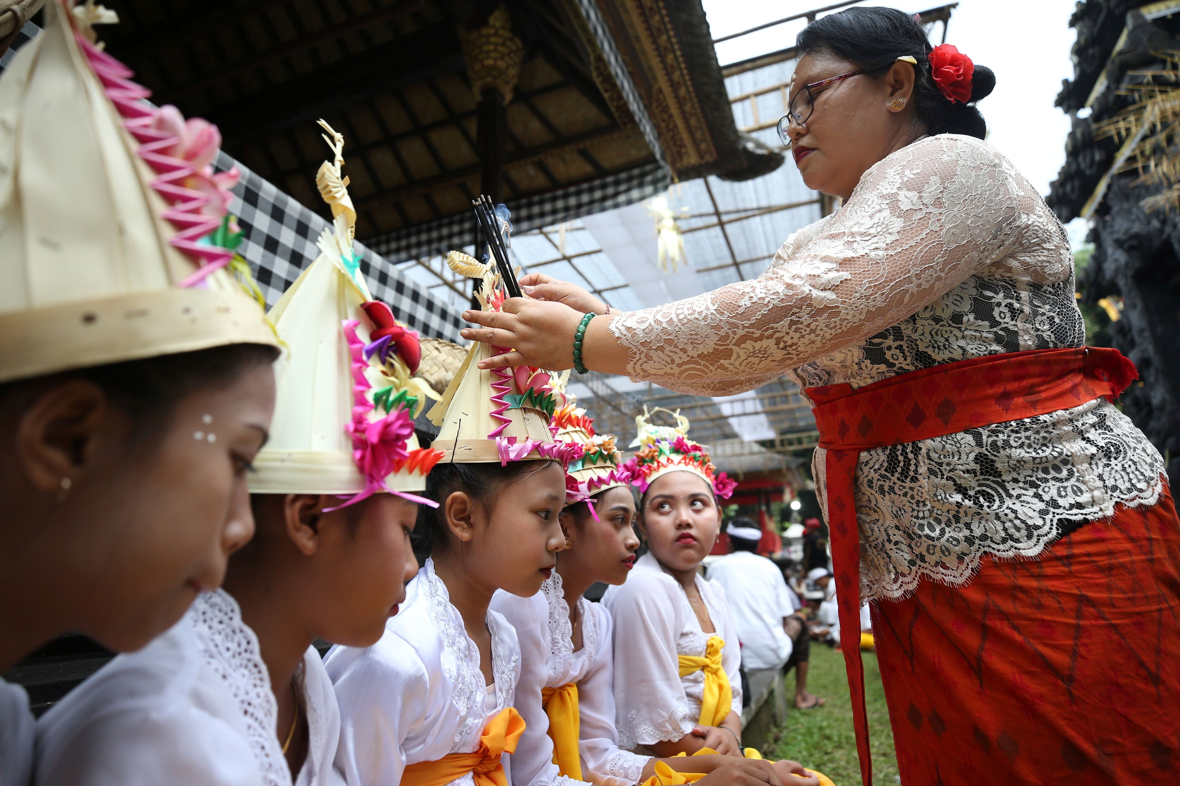 Kadek Krisni fixes an incense stick on the headgear of her daughter Ketut Nita Wahyuni, 11, before a Hindu ritual at Geriana Kauh village, Karangasem, Bali, Indonesia on Wednesday, Nov. 20, 2024. (AP Photo/Firdia Lisnawati)