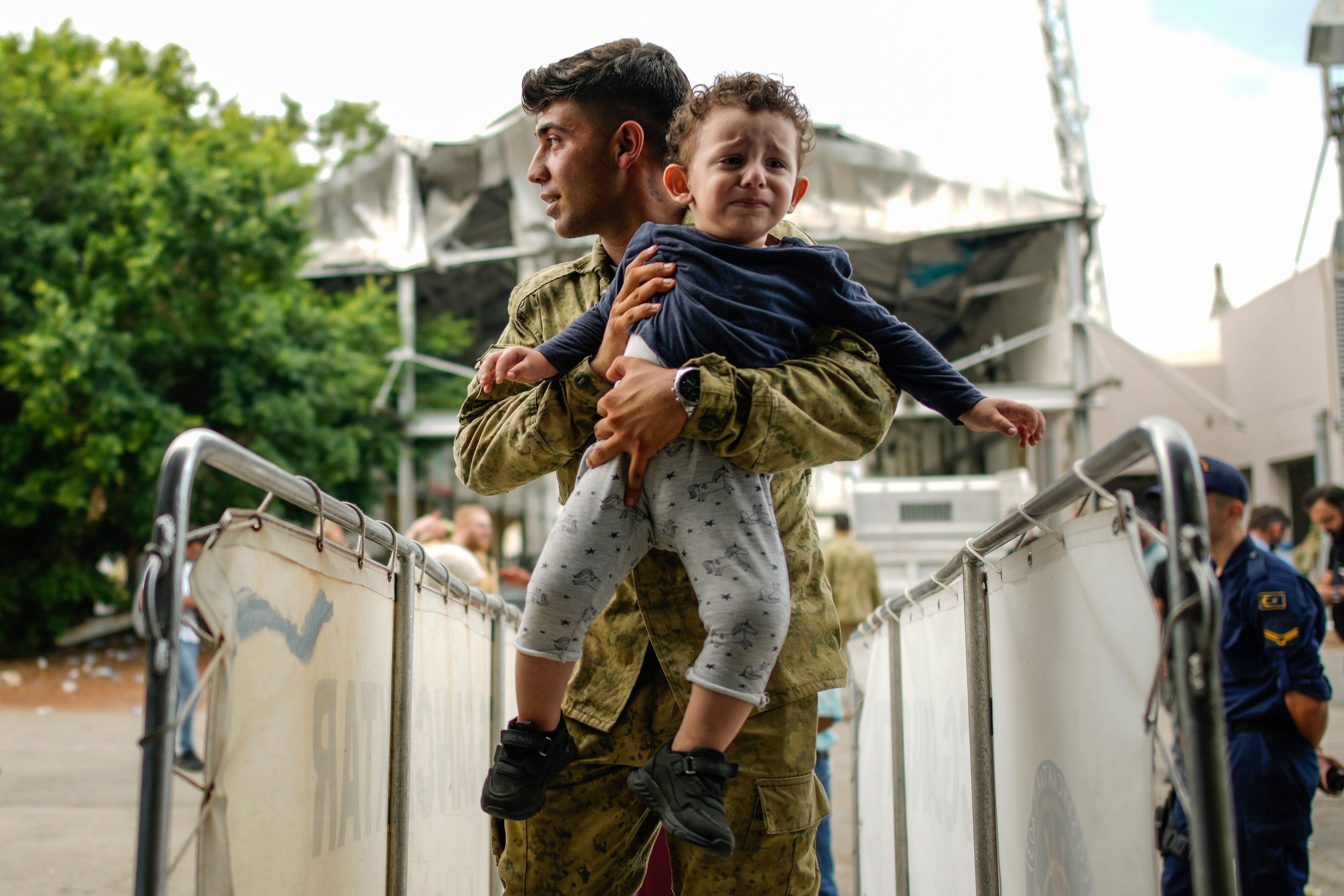 A Turkish military person carries a child on board of a Turkish military ship as he and hundreds of people, mostly Turkish citizens, are evacuated from Lebanon to Turkey, in Beirut port, on Thursday, Oct. 10, 2024. (AP Photo/Emrah Gurel)