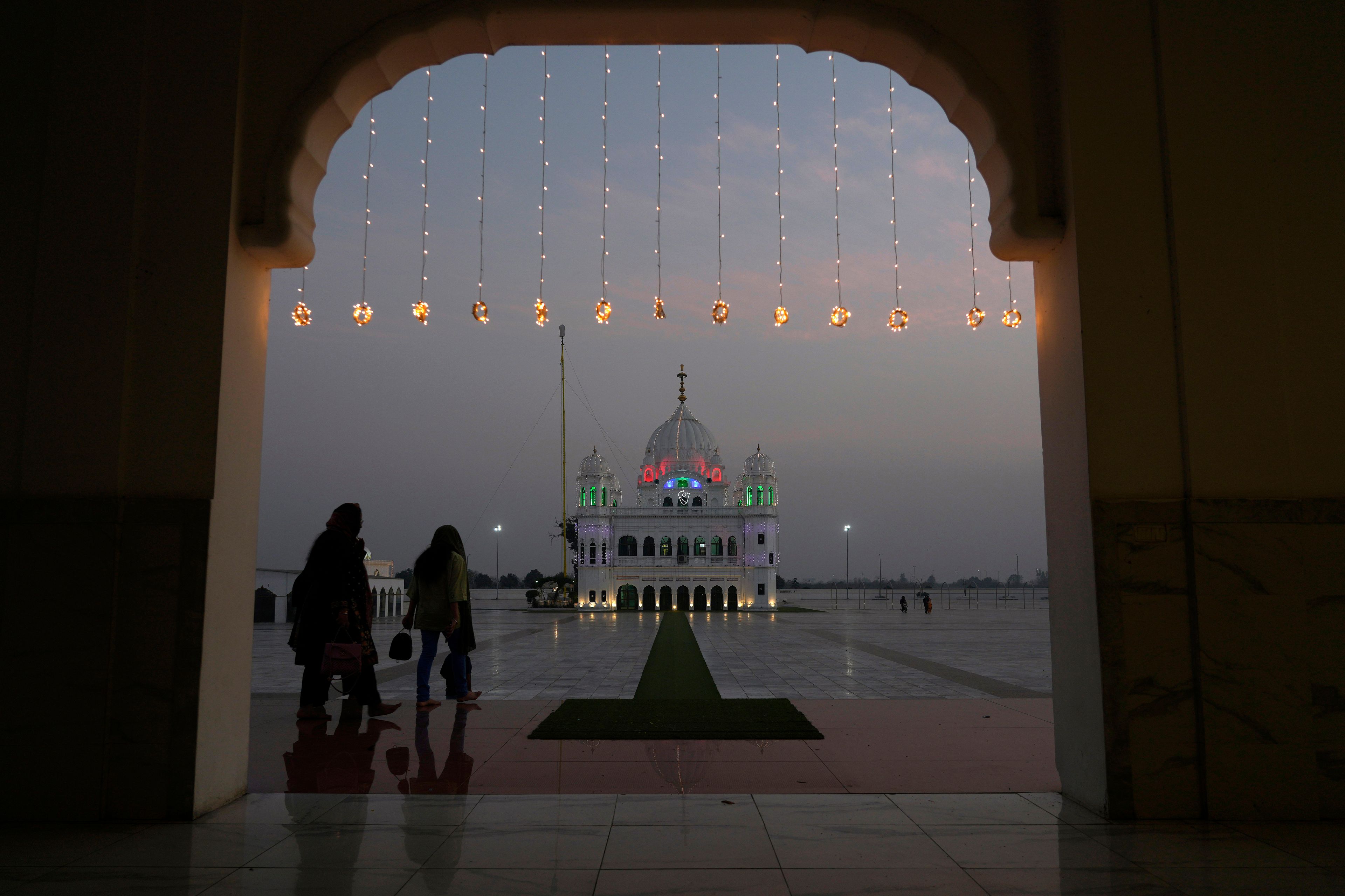 Sikh pilgrims arrive at the shrine of first Sikh guru, Guru Nanak Dev, which is illuminated for the birth anniversary celebrations at the Gurdwara Darbar Sahib in Kartarpur, Pakistan, Monday, Nov. 18, 2024. (AP Photo/Anjum Naveed)