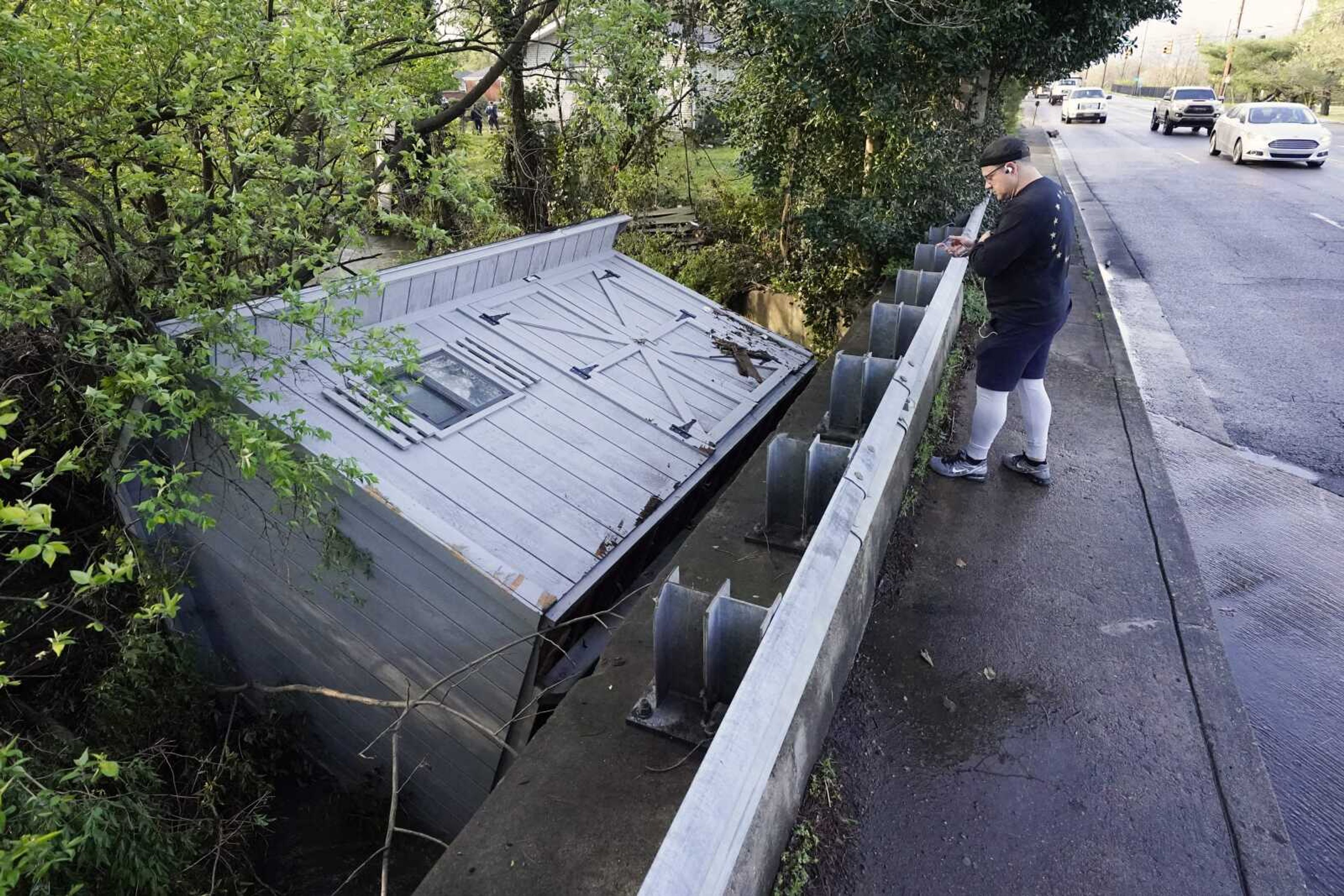 Adam Wirdzek stops to look at a utility building that was carried down a flooded creek Sunday in Nashville, Tennessee.