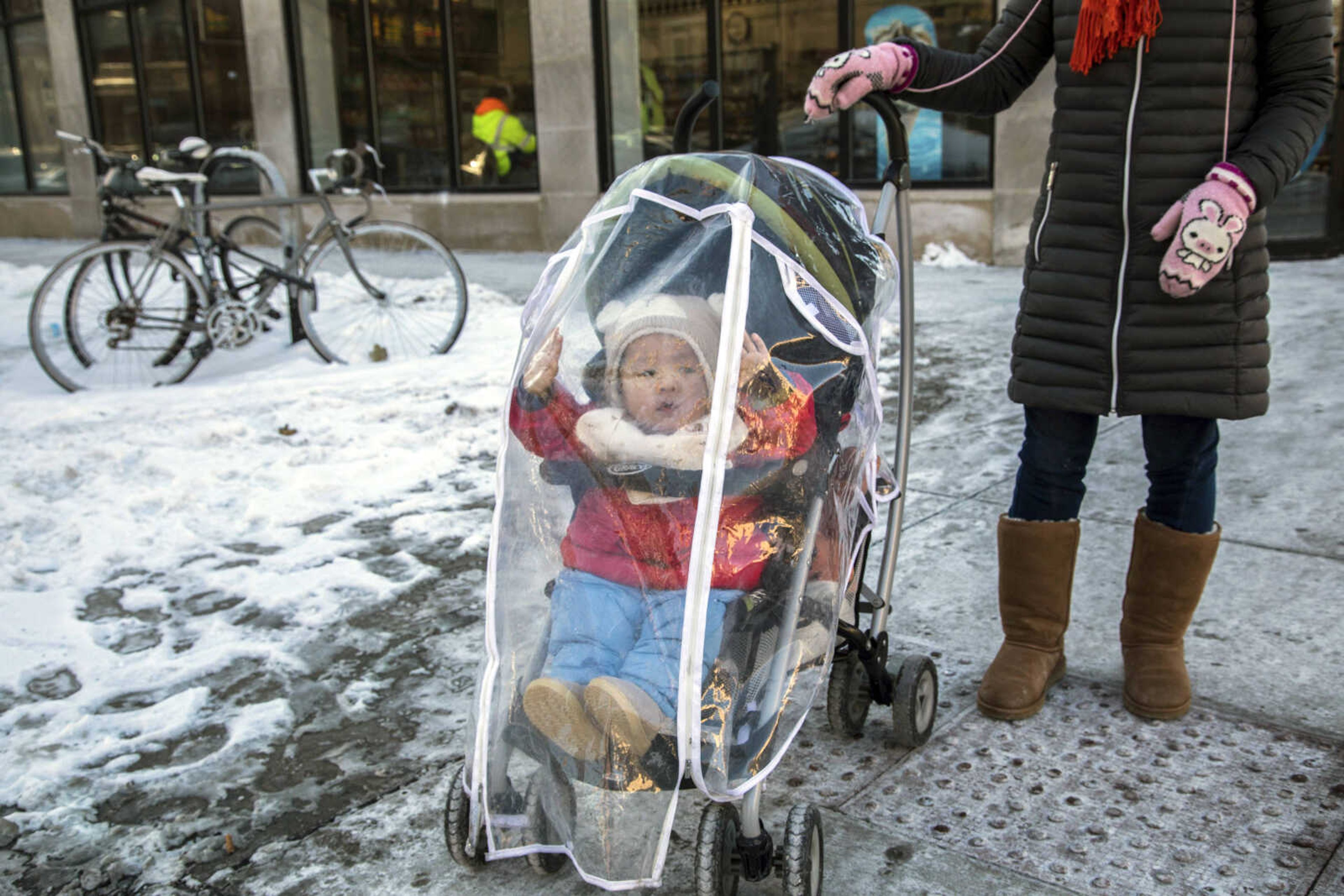 Wen Qin Fu takes her 15-month-old baby Beyu Xia for a walk in a stroller fitted with a cover to protect against the wind in Chicago's Hyde Park during subzero temperatures Tuesday.