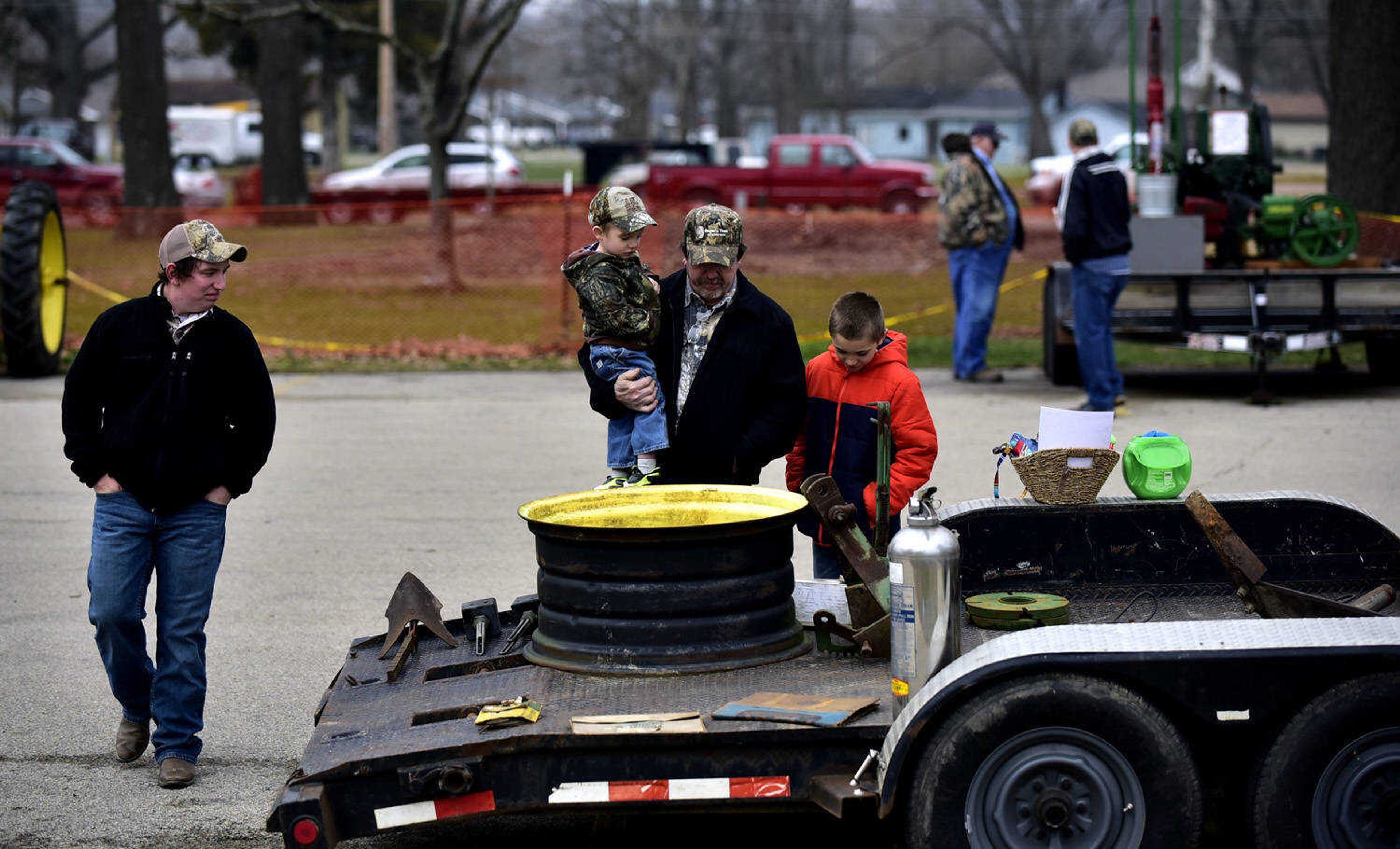 From left, Joe Trankle, Isaac Choate, 3, David Trankle and Logan McDonough, 10, look at farm supplies for sale on a trailer at the Cousin Carl Farm Show on Saturday, March 10, 2018, at Arena Park in Cape Girardeau.