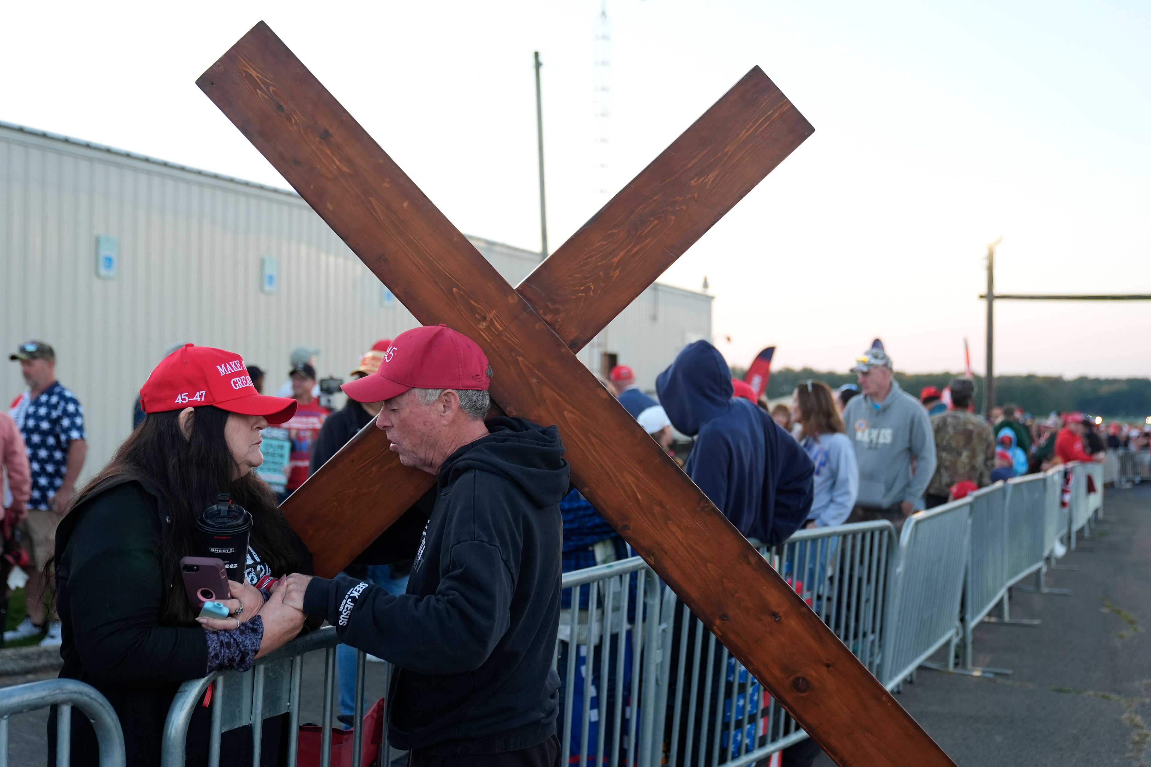 Dan Beasley of Northville, Mich., prays with Sue Hensal of Akron, Ohio, before Republican presidential nominee former President Donald Trump speaks at a campaign rally at the Butler Farm Show, the site where a gunman tried to assassinate him in July, Saturday, Oct. 5, 2024, in Butler, Pa. (AP Photo/Alex Brandon)